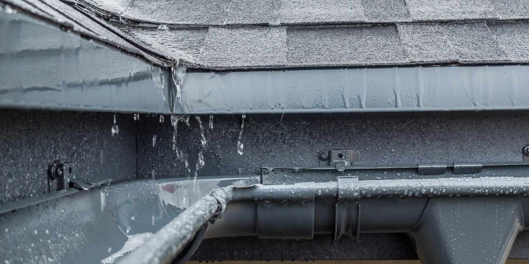 Nahaufnahme einer Dachrinne mit herablaufendem Regenwasser – regelmäßige Wartung schützt vor Wasserschäden und undichten Stellen am Dach. Nahaufnahme einer Dachrinne mit herablaufendem Regenwasser – regelmäßige Wartung schützt vor Wasserschäden und undichten Stellen am Dach.