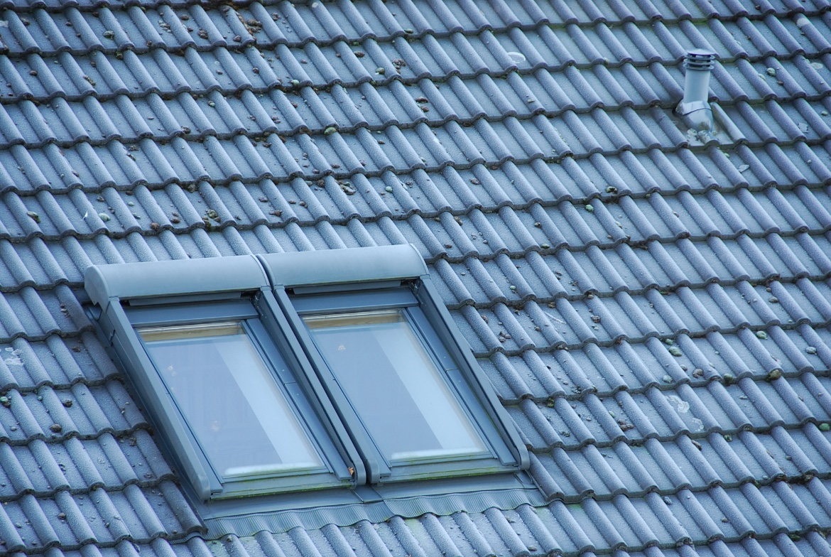 Zwei geschlossene Dachfenster in einem Ziegeldach mit Frost