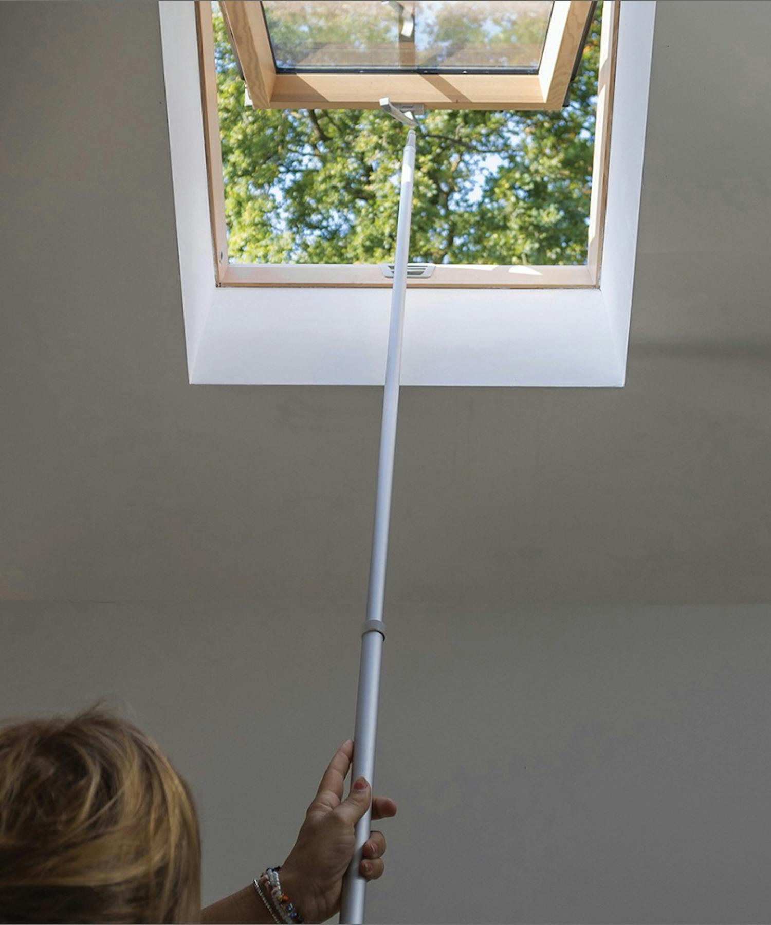 Frau öffnet Roto Dachfenster mit Öffnungshilfe Frau öffnet Roto Dachfenster mit Öffnungshilfe