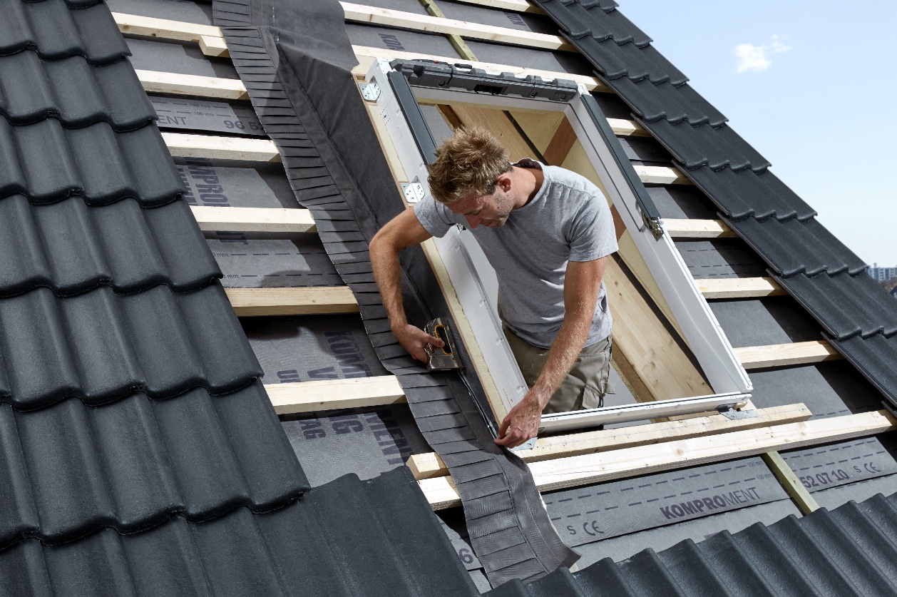 Handwerker dichtet ein Dachfenster von Velux ab