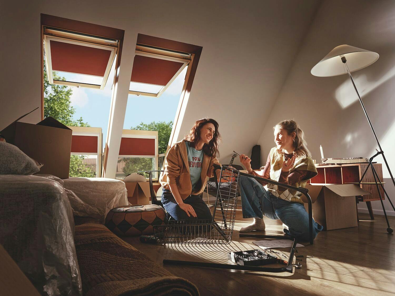 Zwei Frauen bauen Möbel in einem Wohnzimmer mit Fakro Balkonfenstern auf