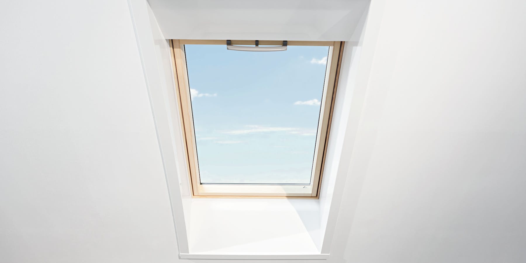 Roto Dachfenster in weißer Wand mit Blick in den blauen Himmel Roto Dachfenster in weißer Wand mit Blick in den blauen Himmel
