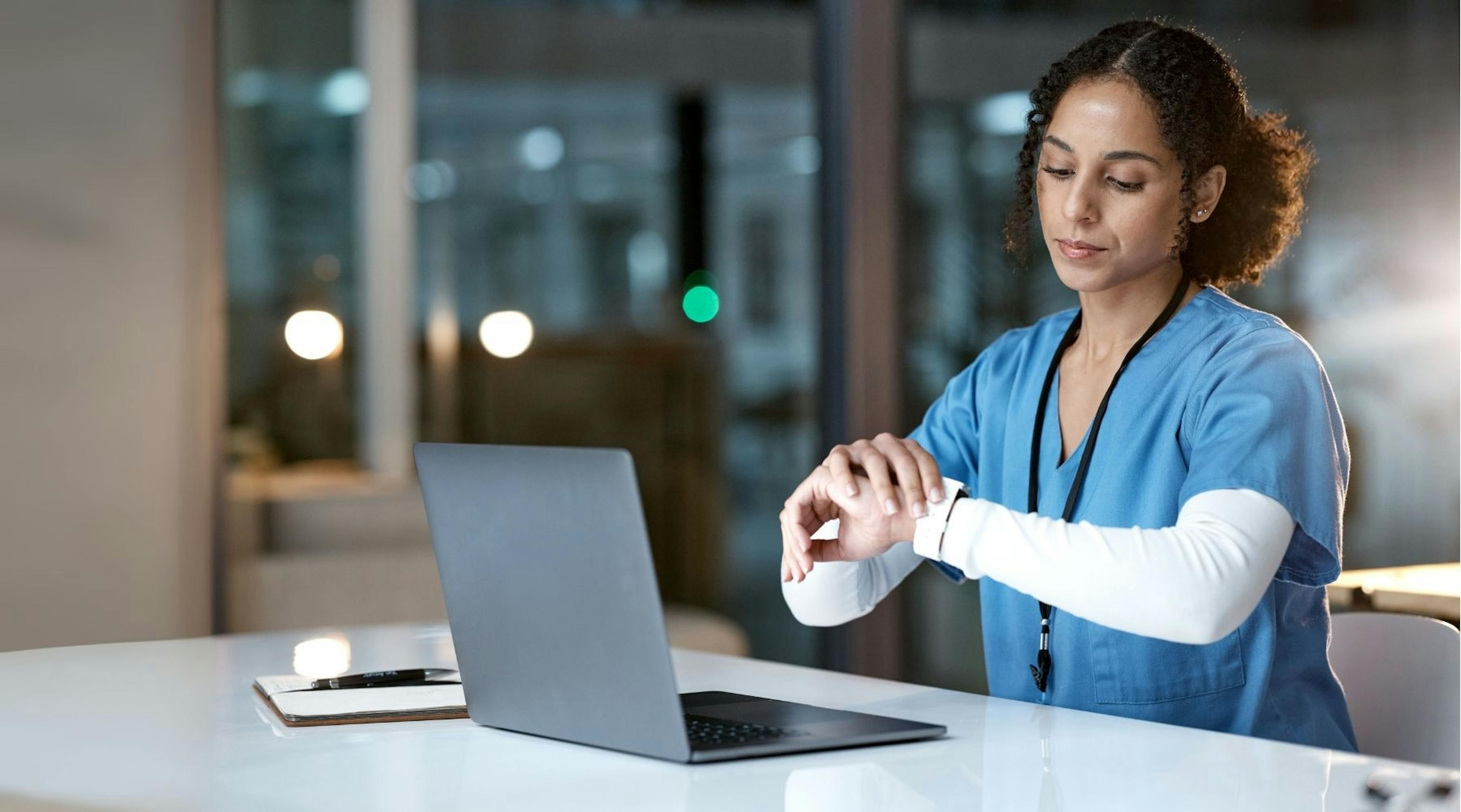 Arbeitszeitgesetz: Medizinische Fachkraft blickt auf ihre Armbanduhr