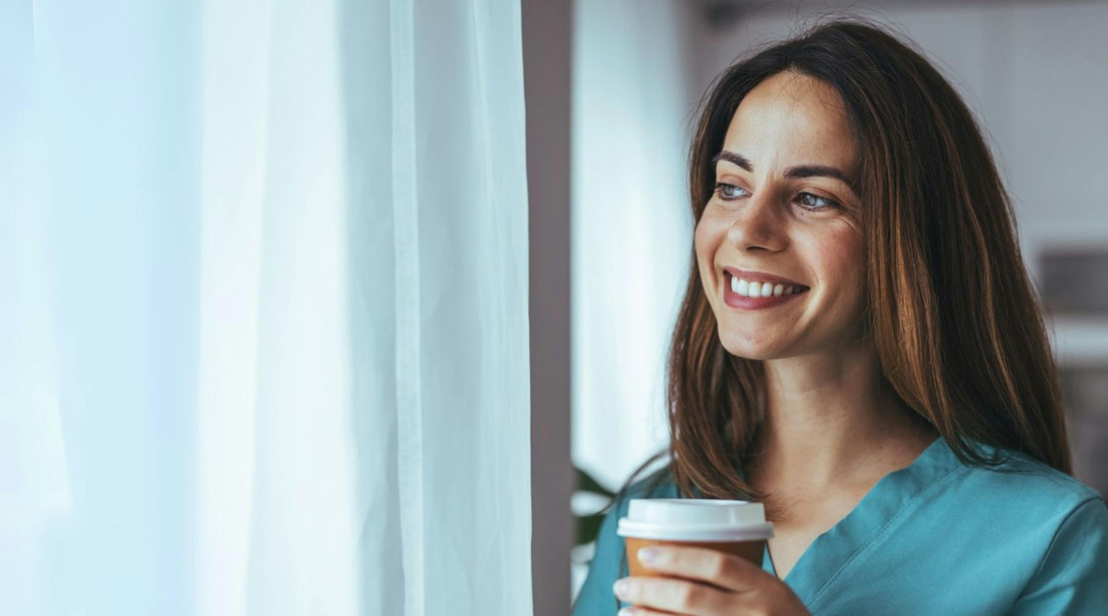 Eine junge, medizinische Fachkraft trinkt entspannt einen Kaffee.