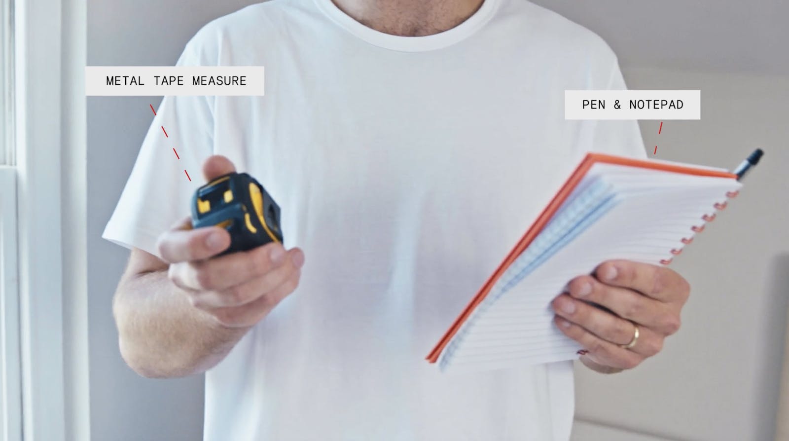 Man holding metal tape measure and pen & notepad