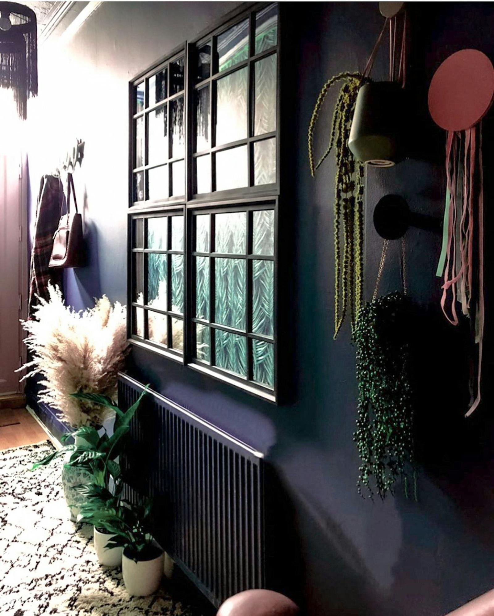 Hallway painted in black with a lot of greenery