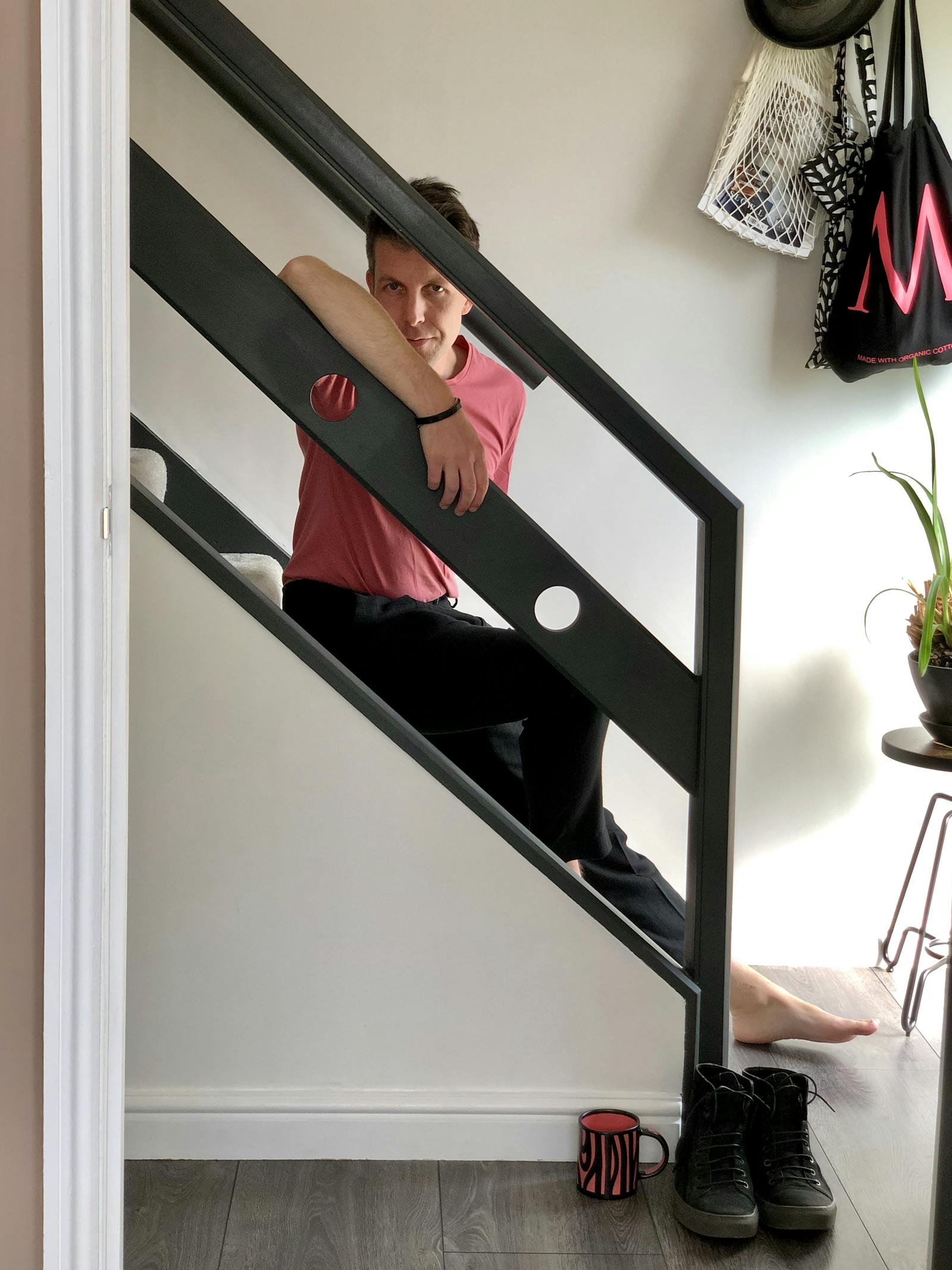 Man wearing red tshirt sitting on black stairs barefooted