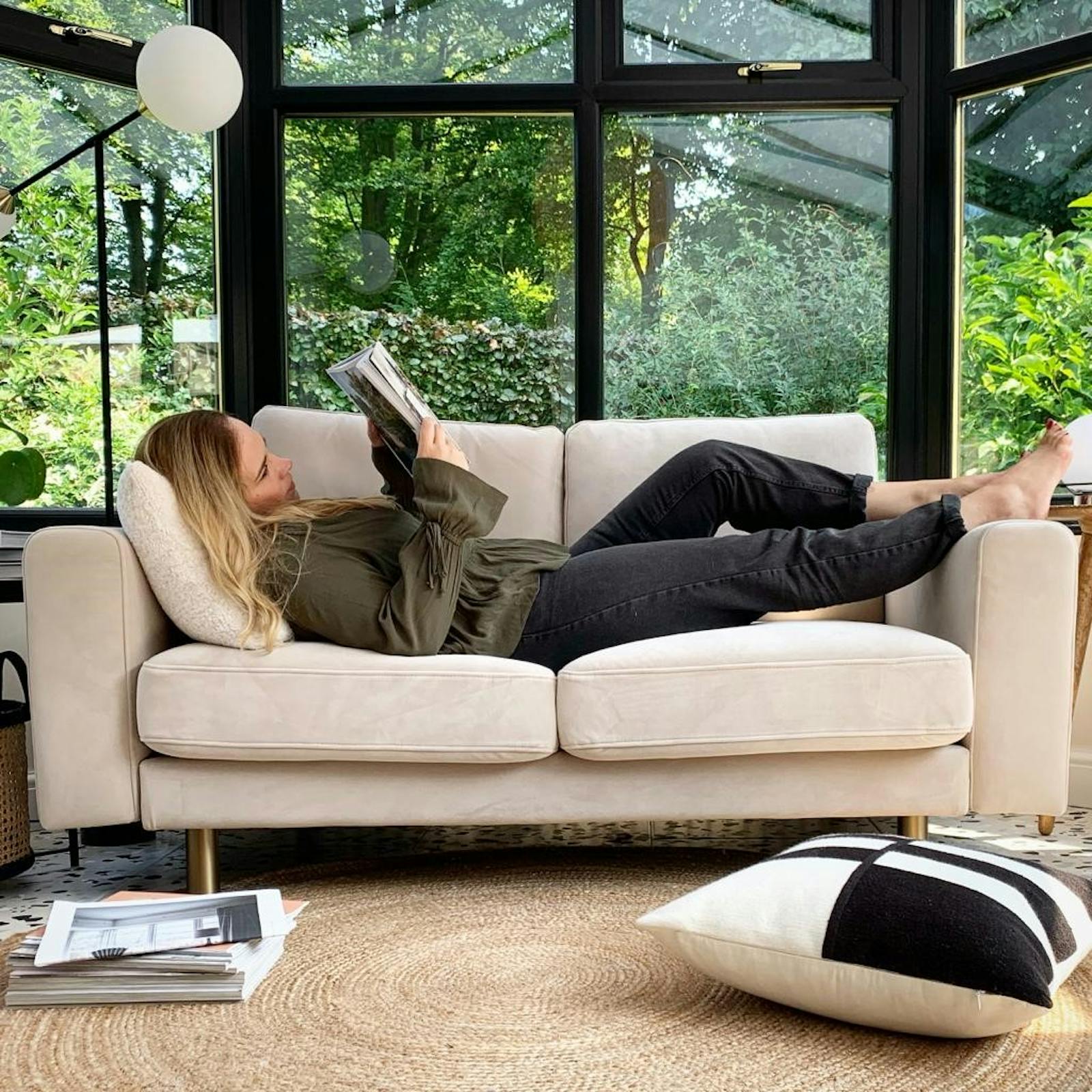 Woman reading a magazine whilst lying on a sofa