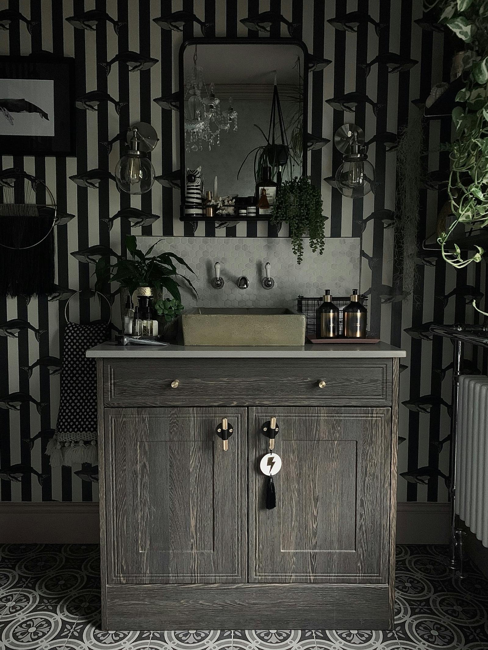 Bathroom in dark colours with lightbulbs and greenery