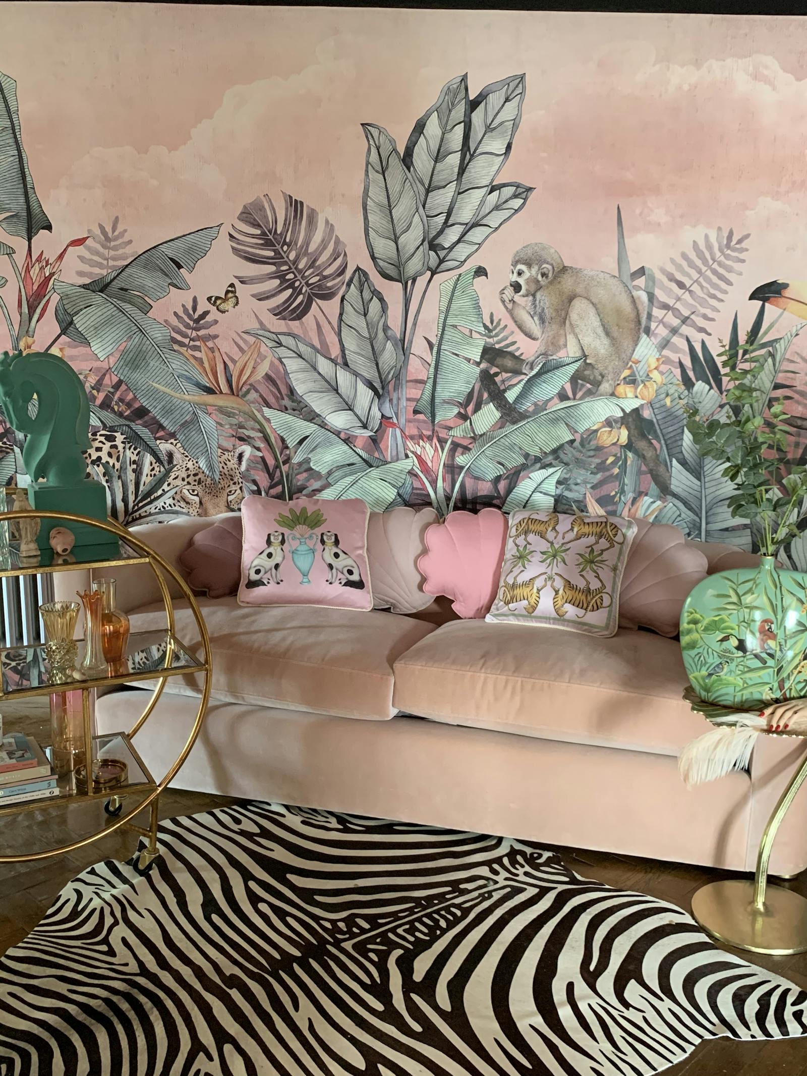 living room area - sofa placed in front of wallpaper with animals, in front of the sofa there's a zebra skin rug