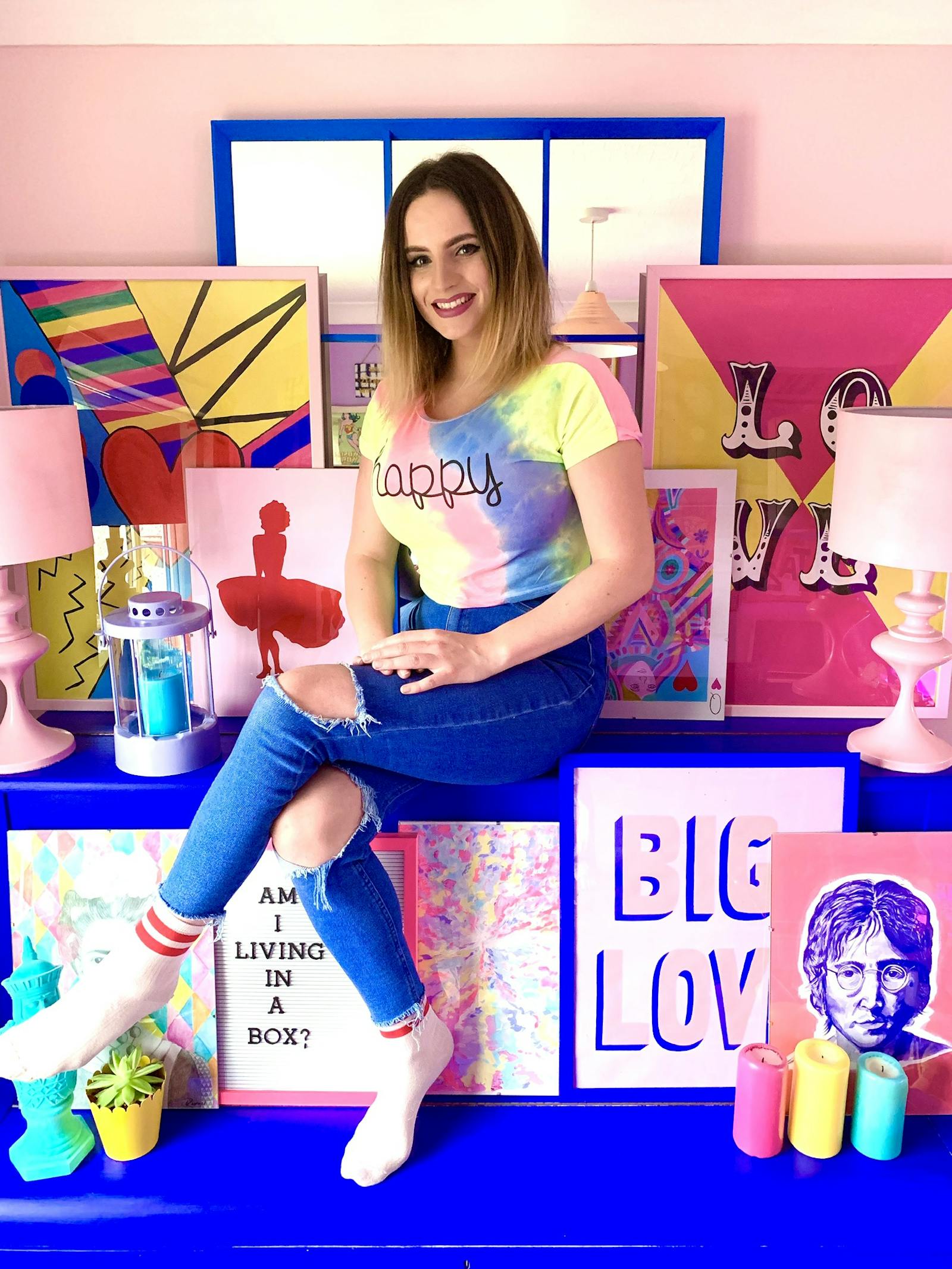 Brunette woman wearing a colourful tshirt and surrounded by blue and pink prints