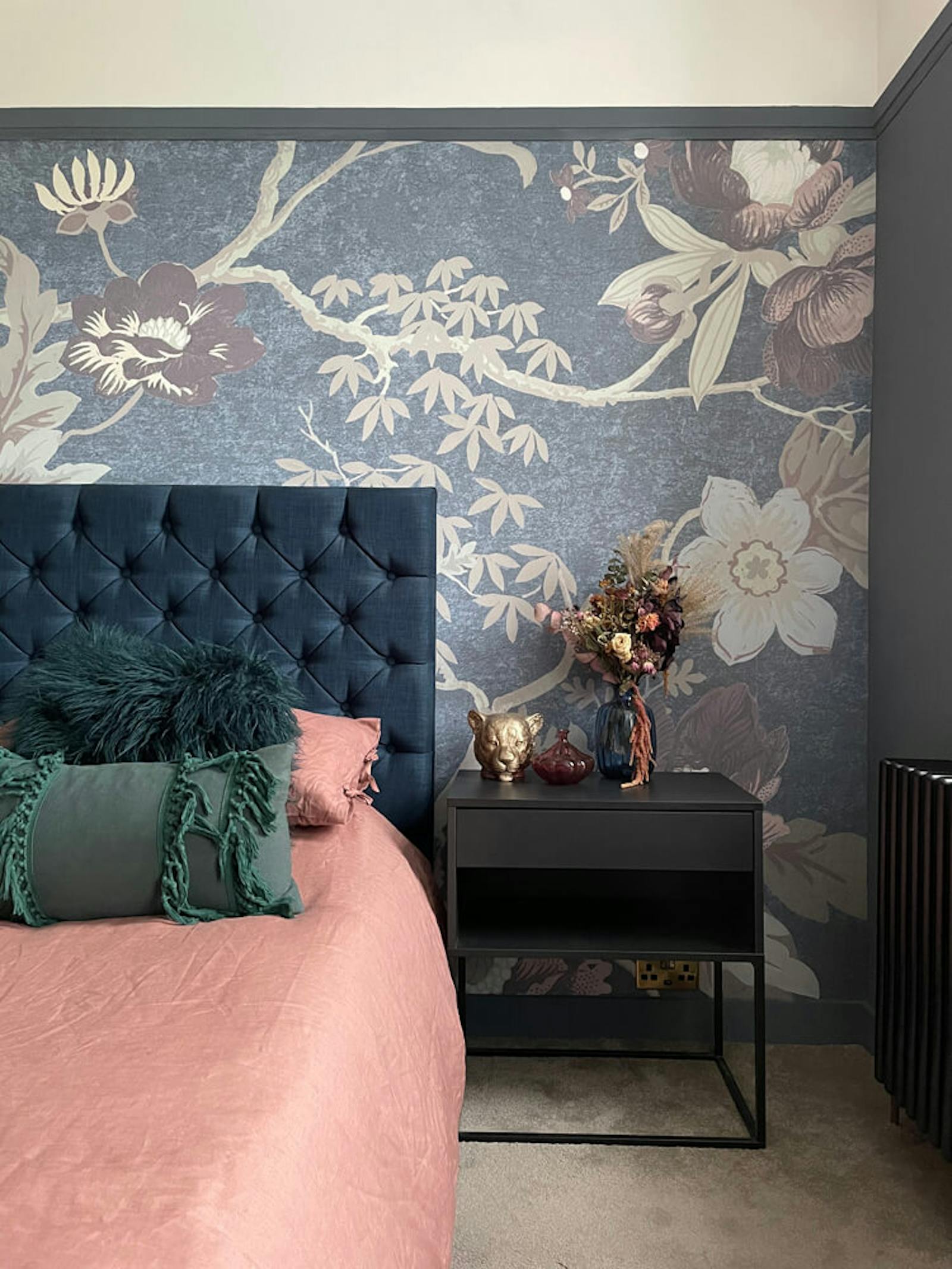 Bedroom with dried flowers and floral wallpaper behind the headboard