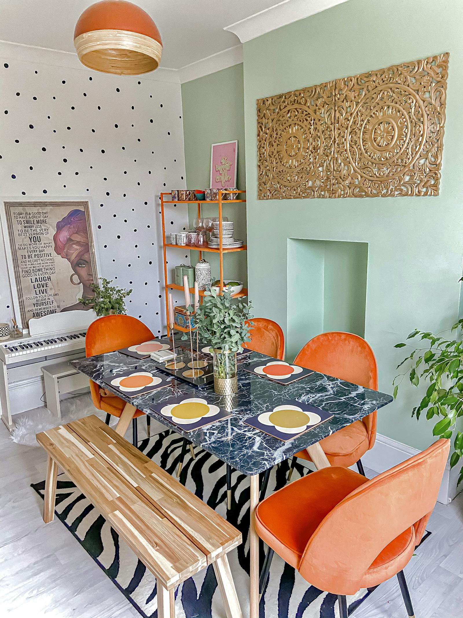 Brightly coloured dining room with polkadot wallpaper, mint green wall feature wall and orange chairs