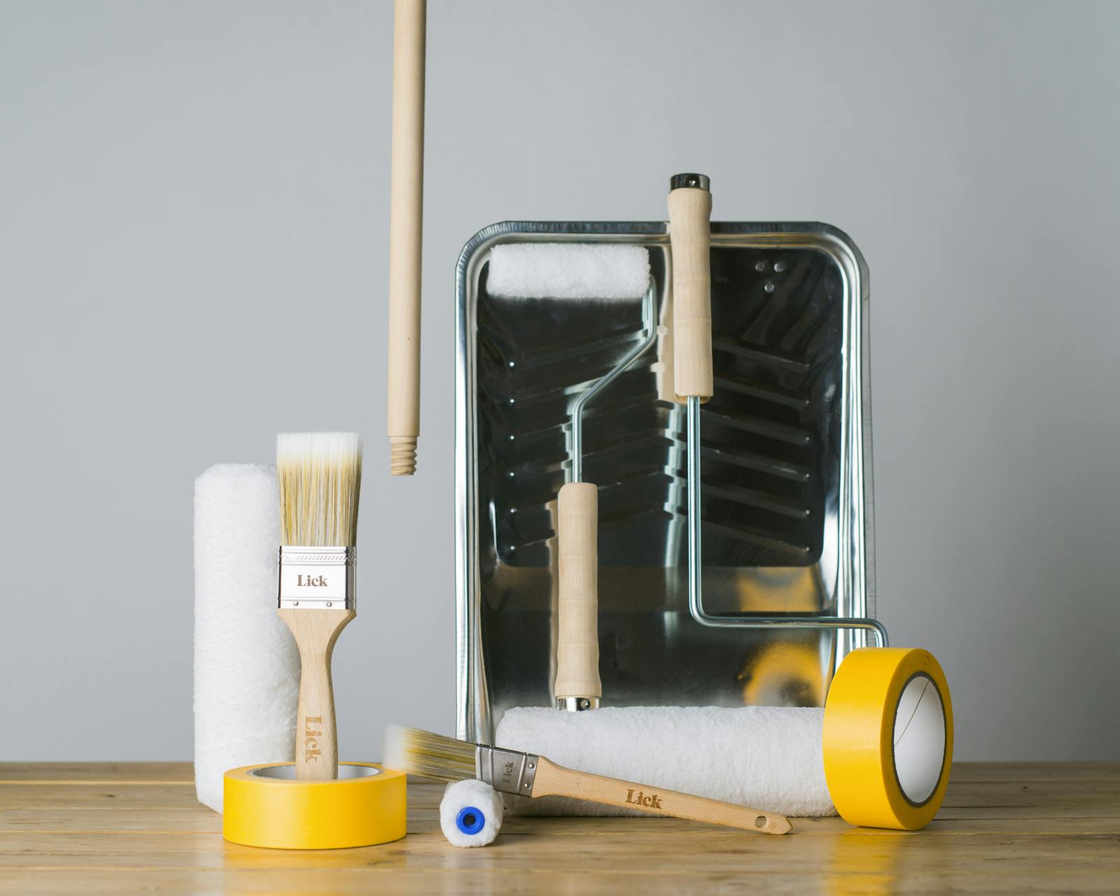 A collection of Lick painting and decorating tools including yellow tape, brushes, rollers and a tray.