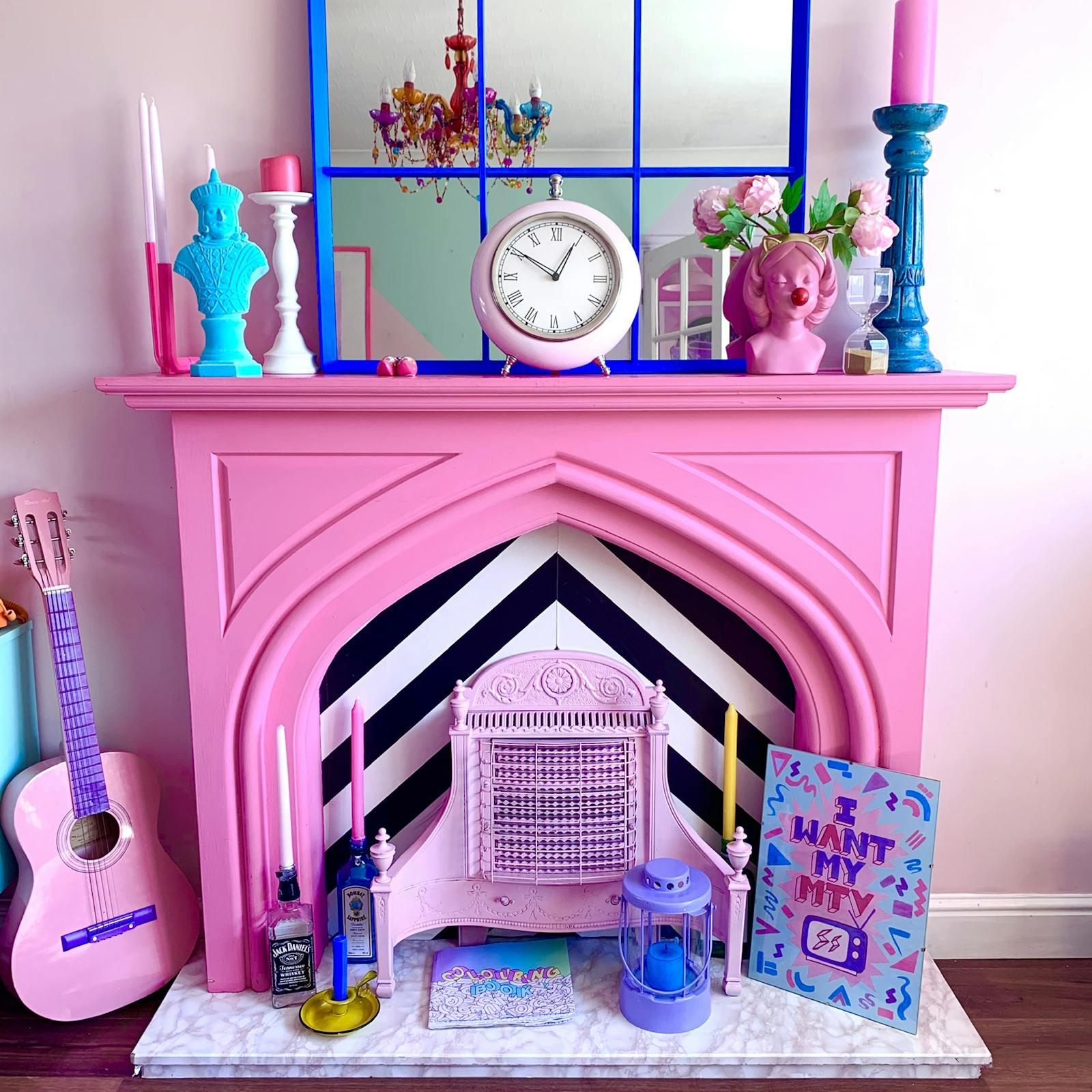 Pink fireplace with an assortment of candles and art work