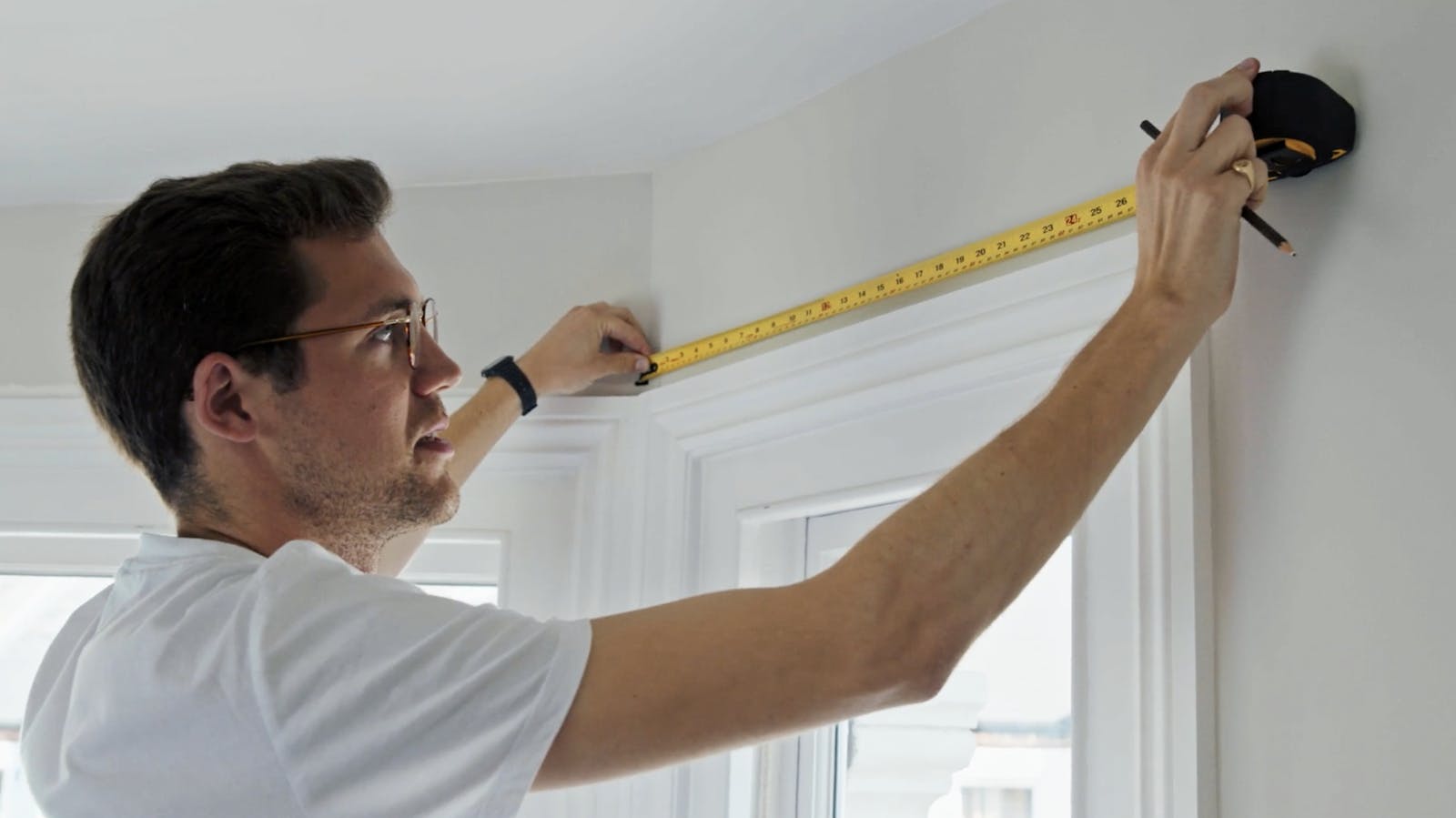 Man holding measuring tape against white wall