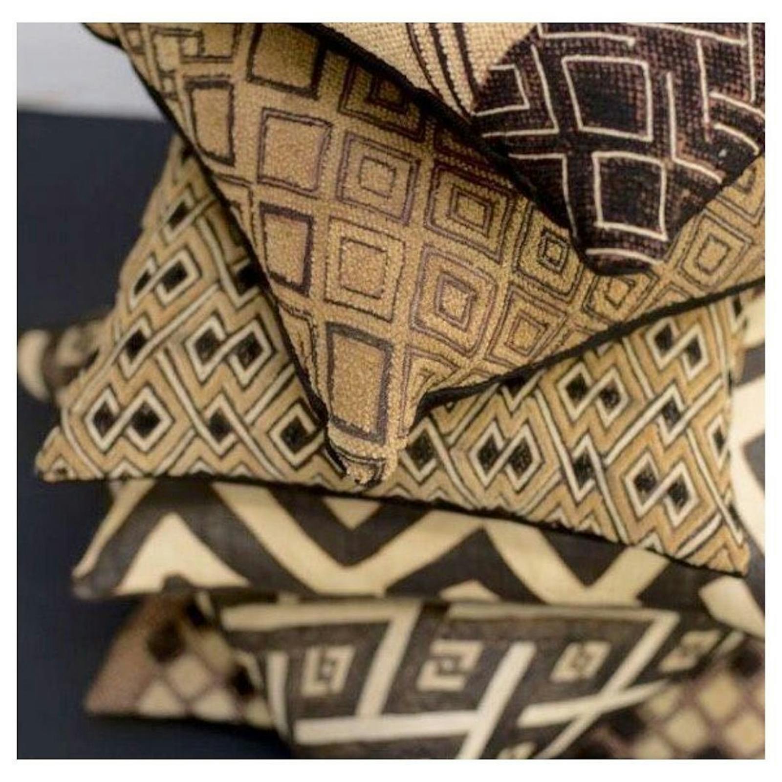 A stack of pillows in African designs in a kuba / raffia material