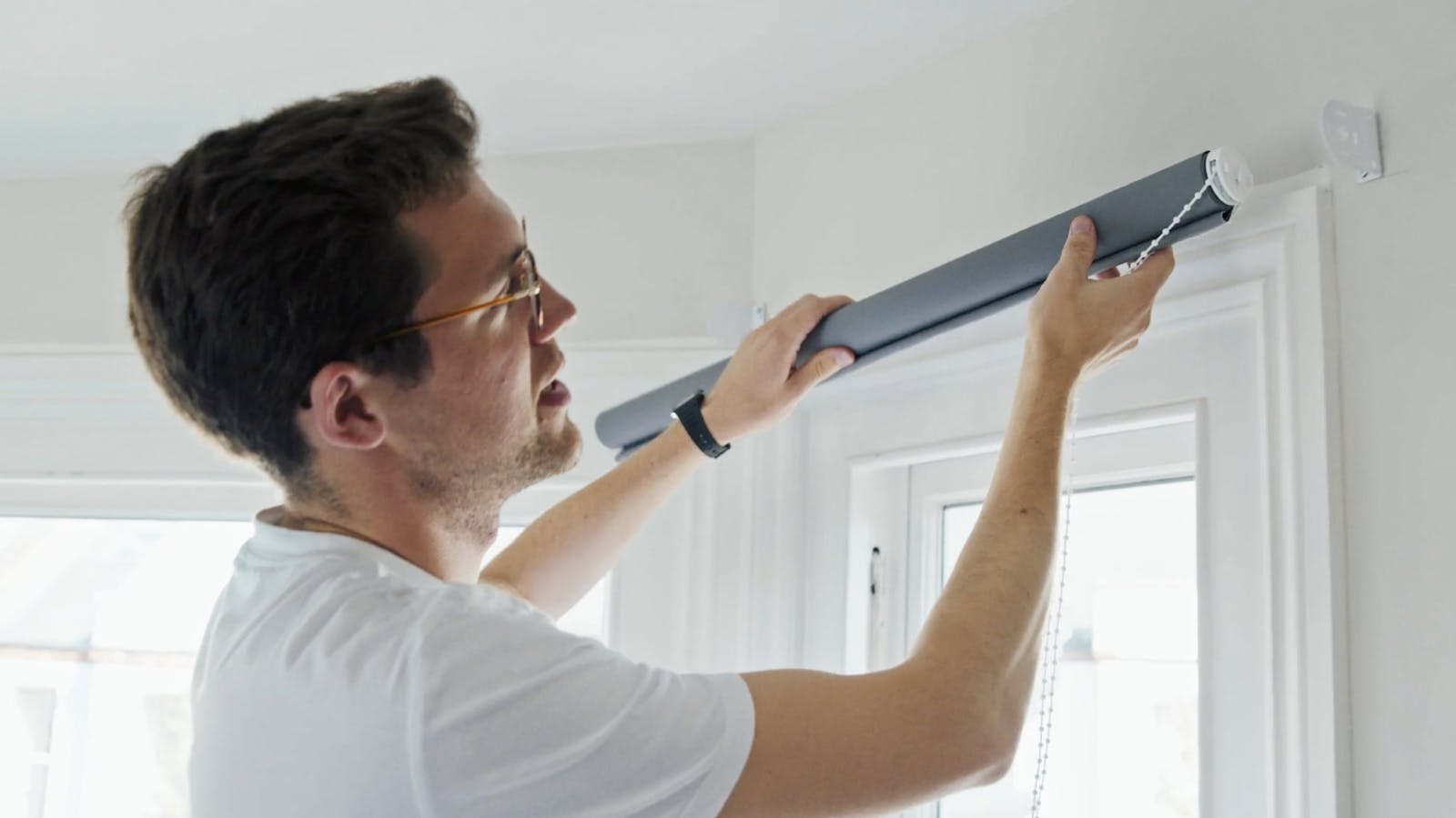 Man holding grey roller blinds in hand