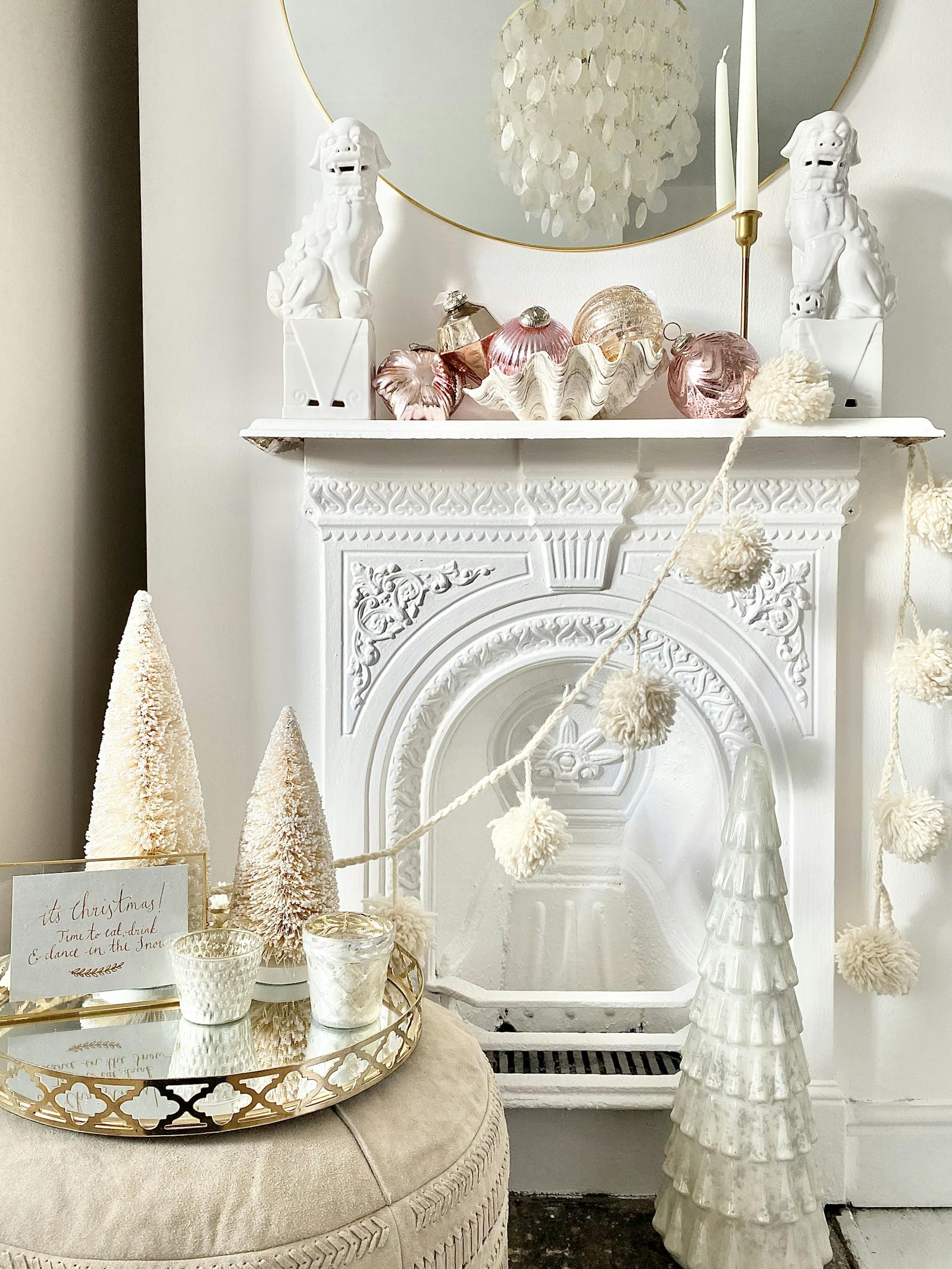 White fireplace with various Christmas decorations and a white garland