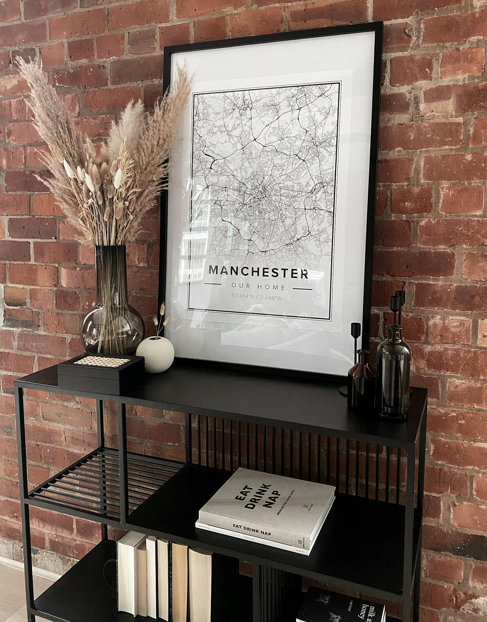 Exposed brick wall with a Manchester map poster and books