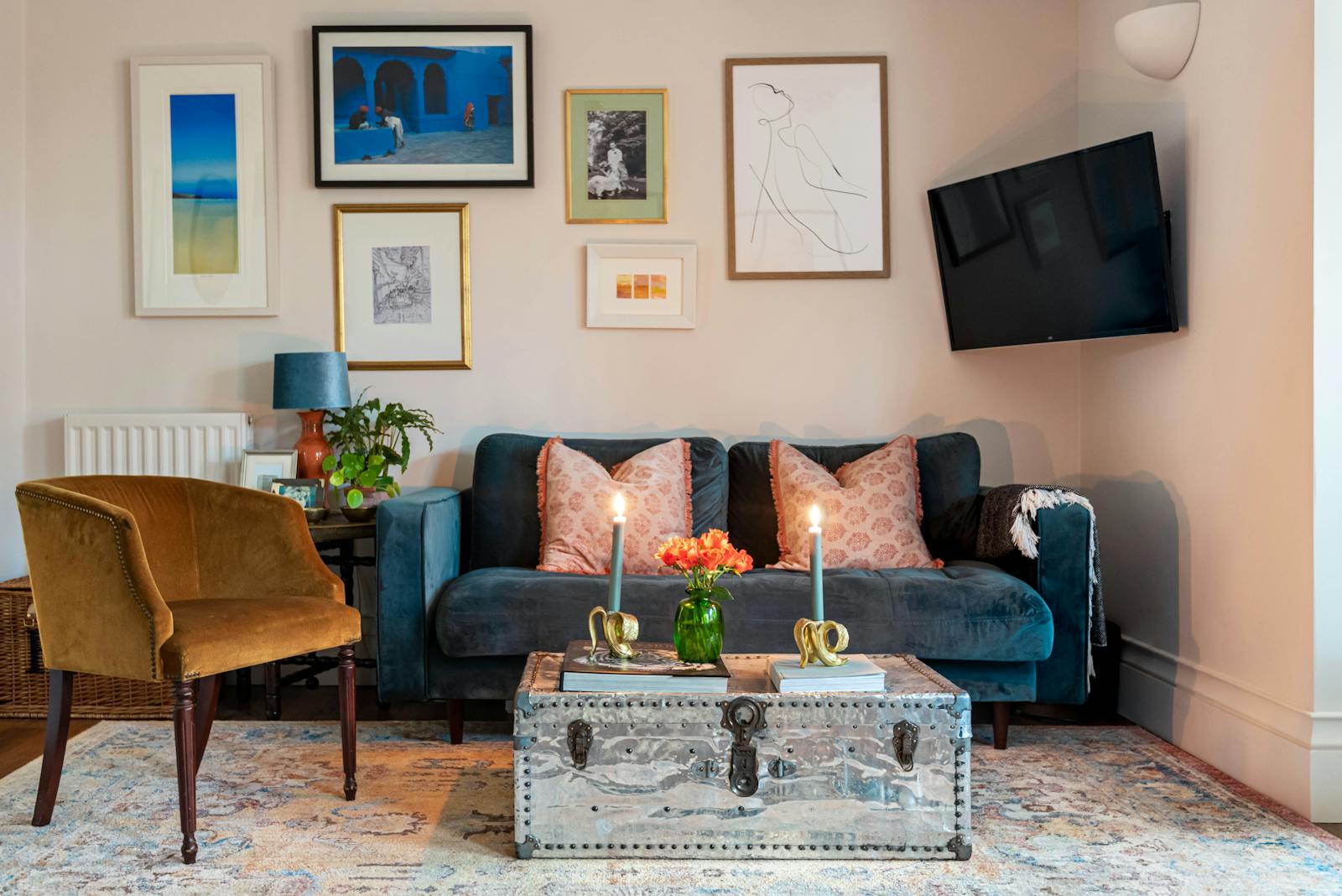 Living room with wall art, mustard and dark blue sofas and candles