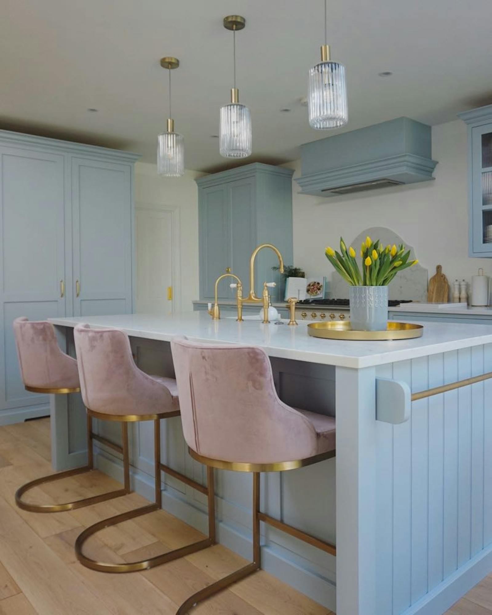 Light blue kitchen with pink velvety chairs