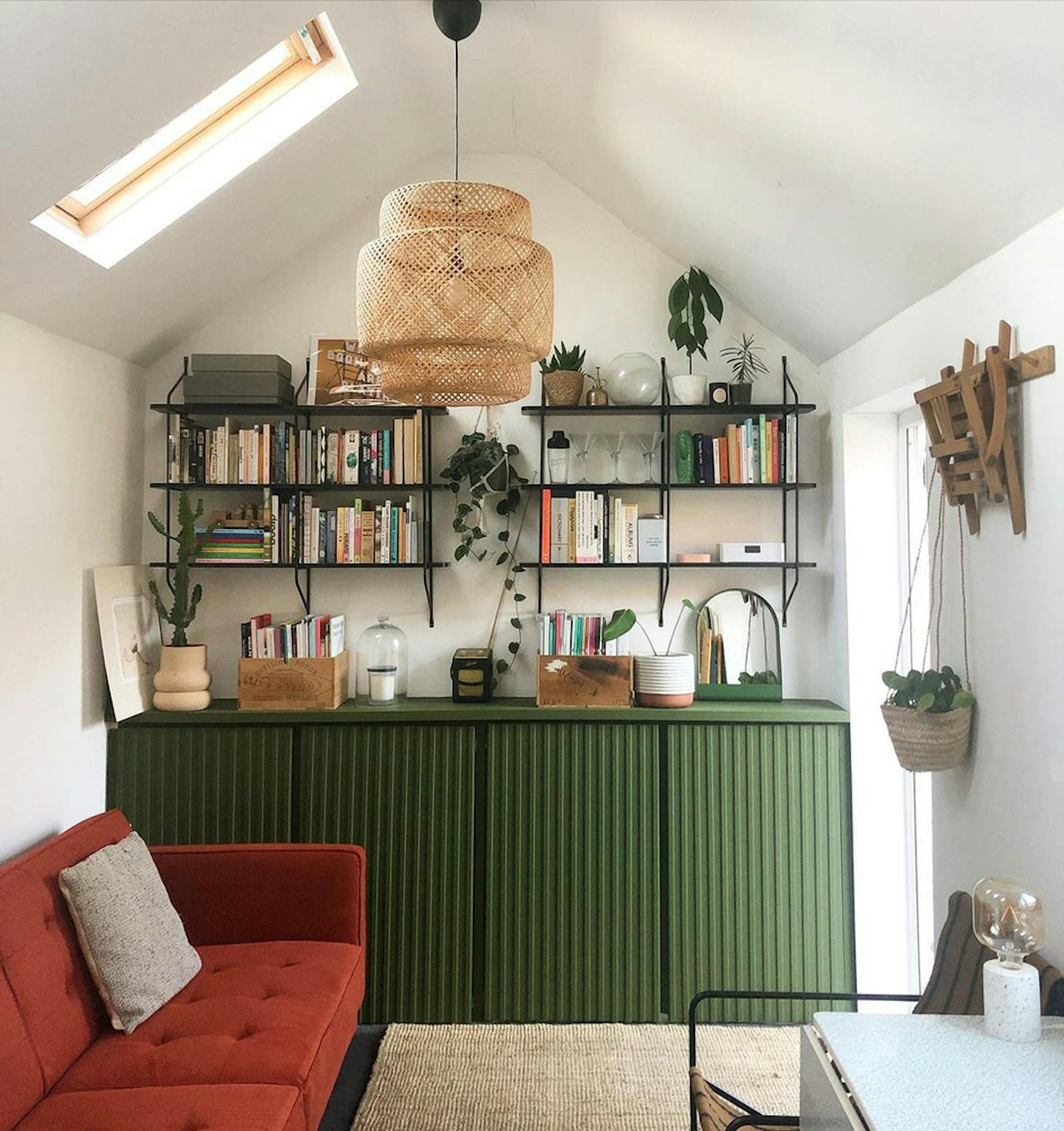 Open shelving on top of green cupboards and hanging plants