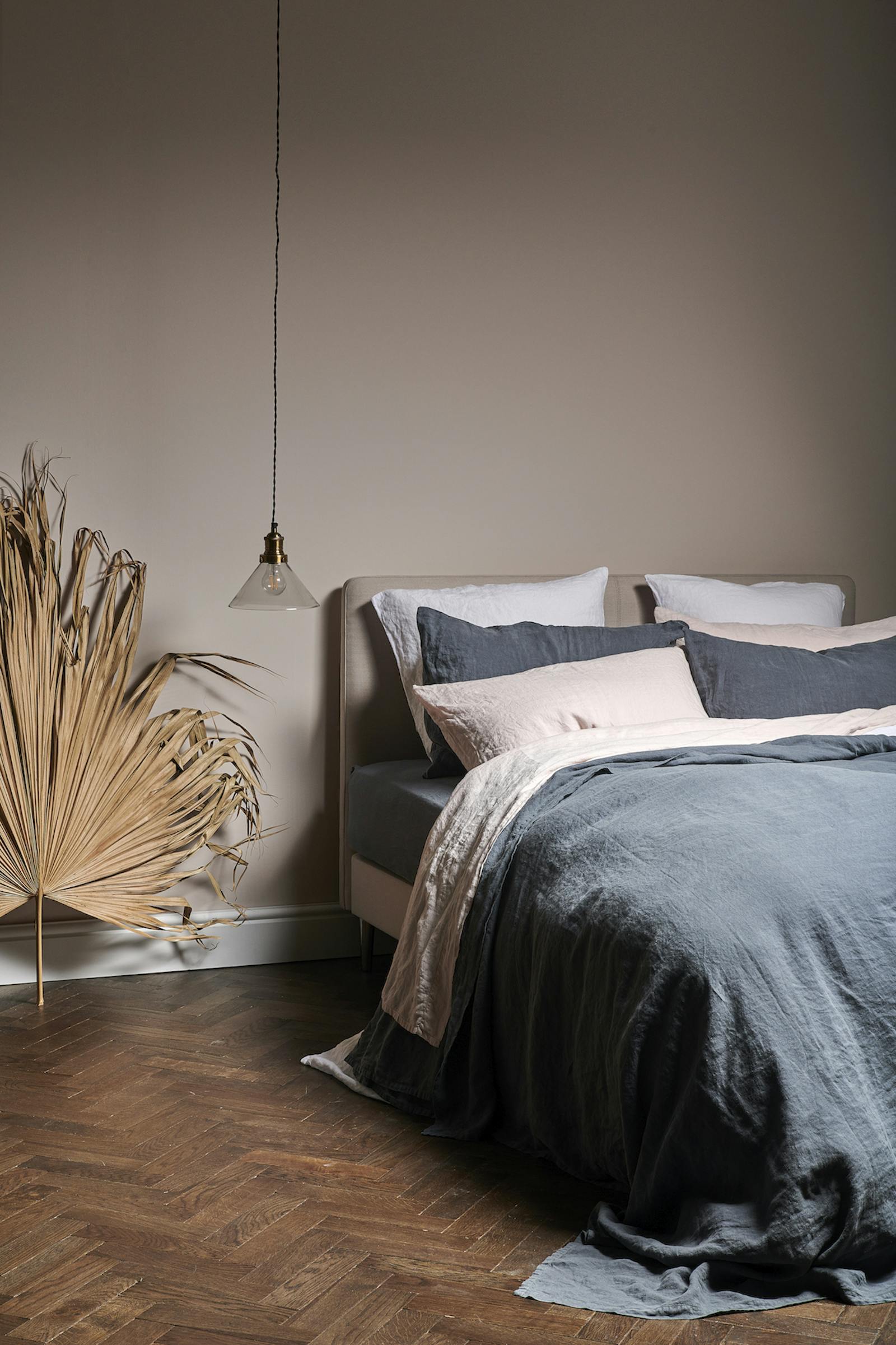 Tranquil bedroom with muted colours and layered linen bedding in beige and ink blue