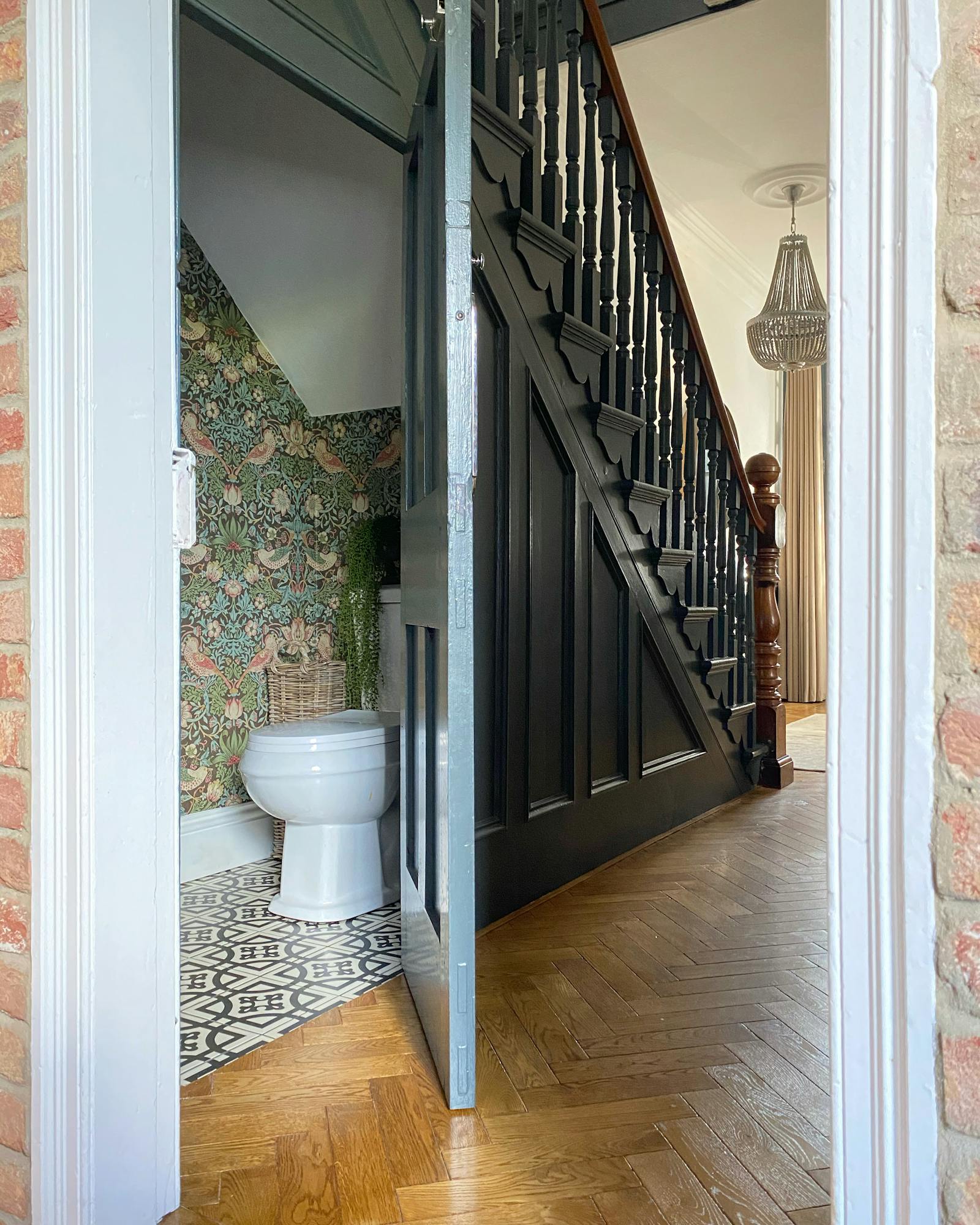 Downstairs toilet with wallpaper and an open door leading to the hallway