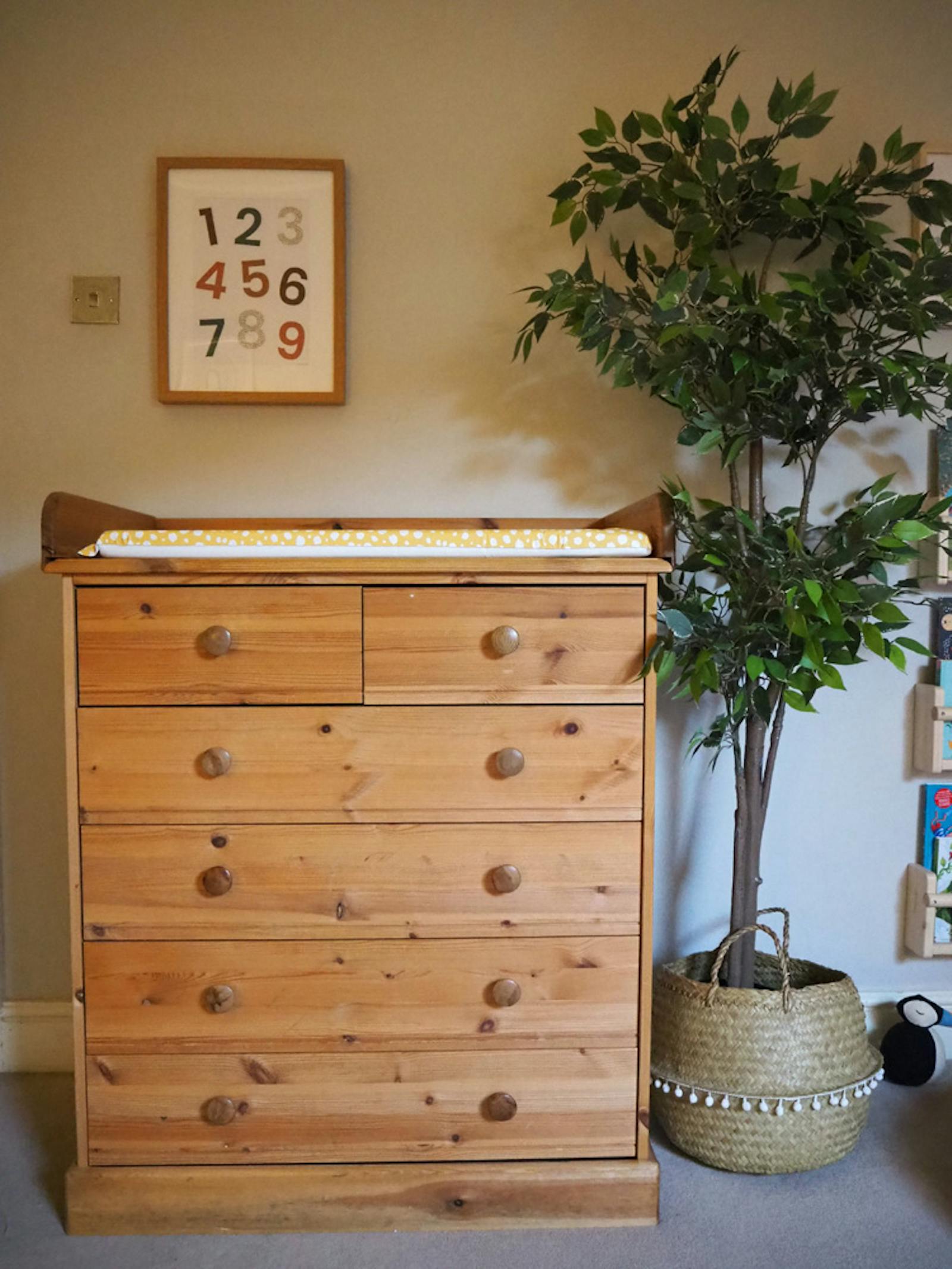 Image of baby changing table with a house plant next to it