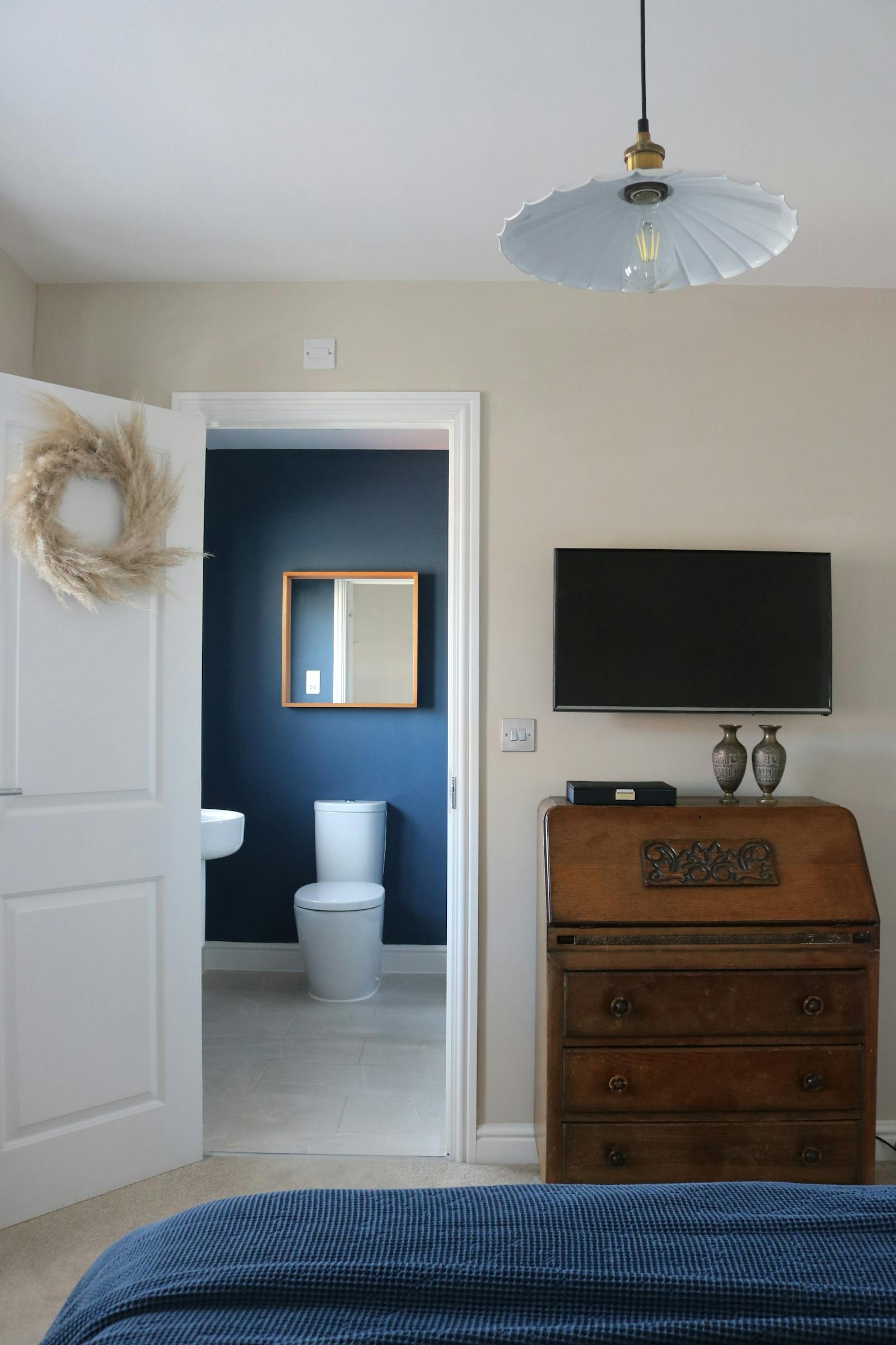 A view from a bedroom showing a blue-painted bathroom