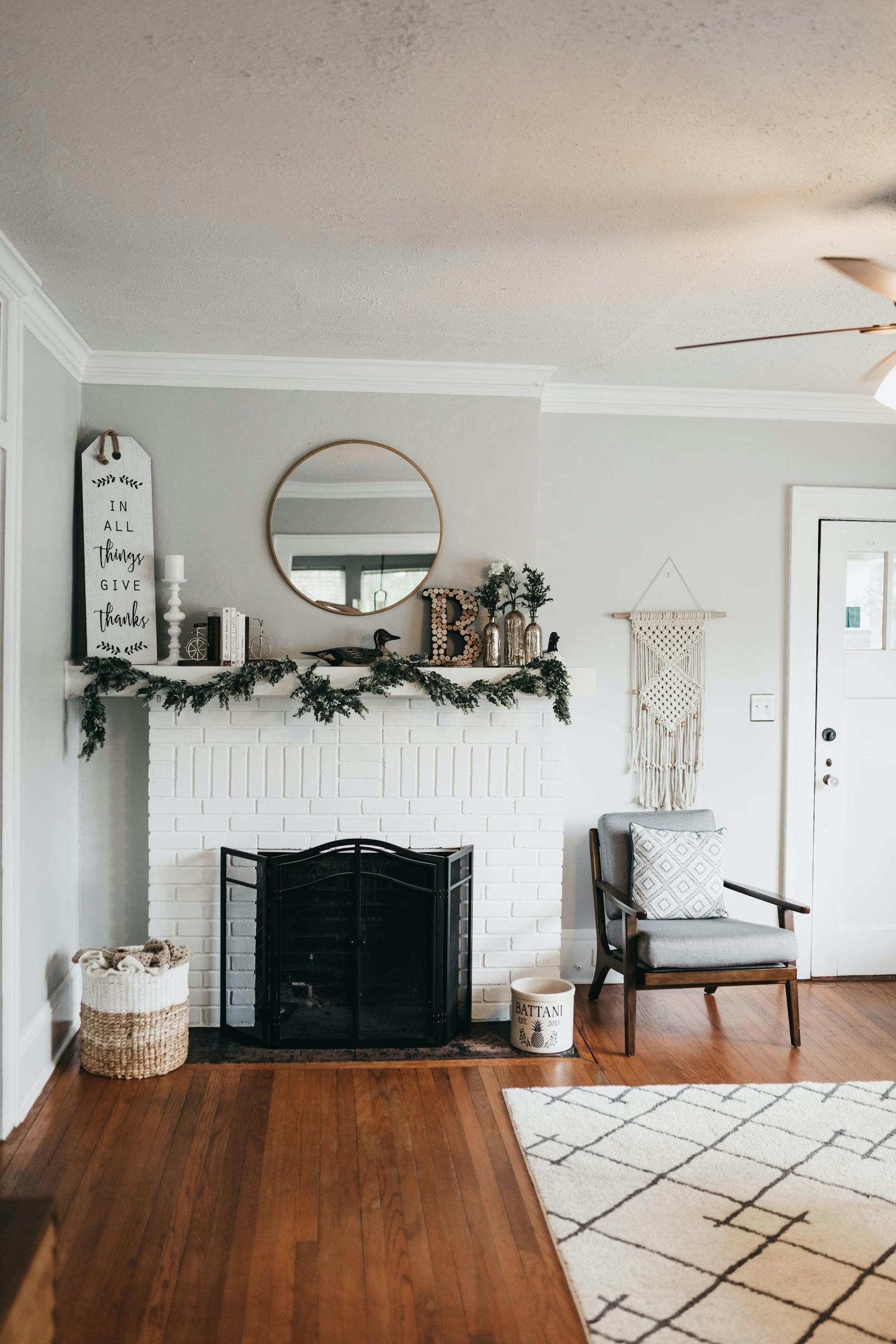 White room with circular mirror above fireplace
