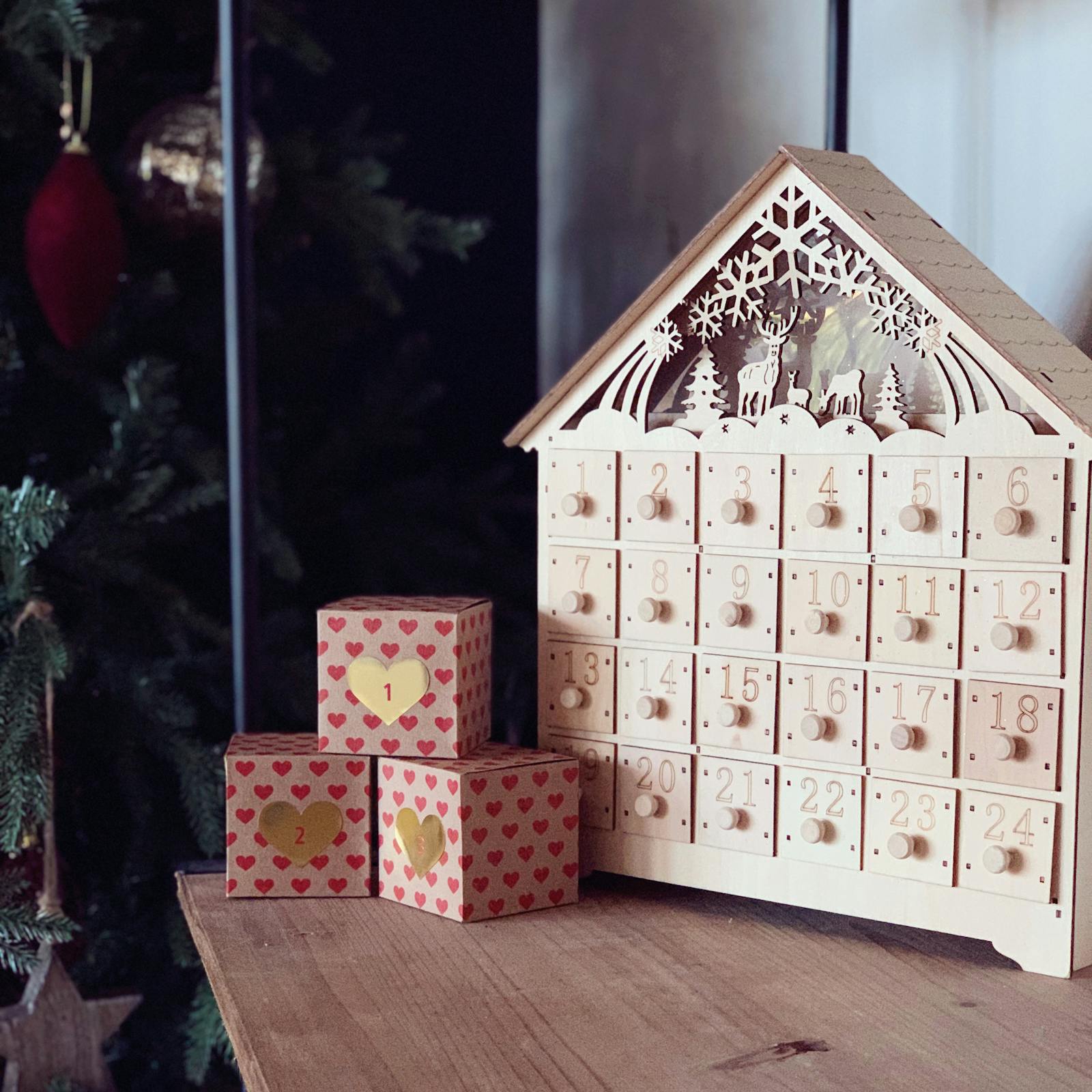 Wooden advent calendar next to Christmas wrapped gifts
