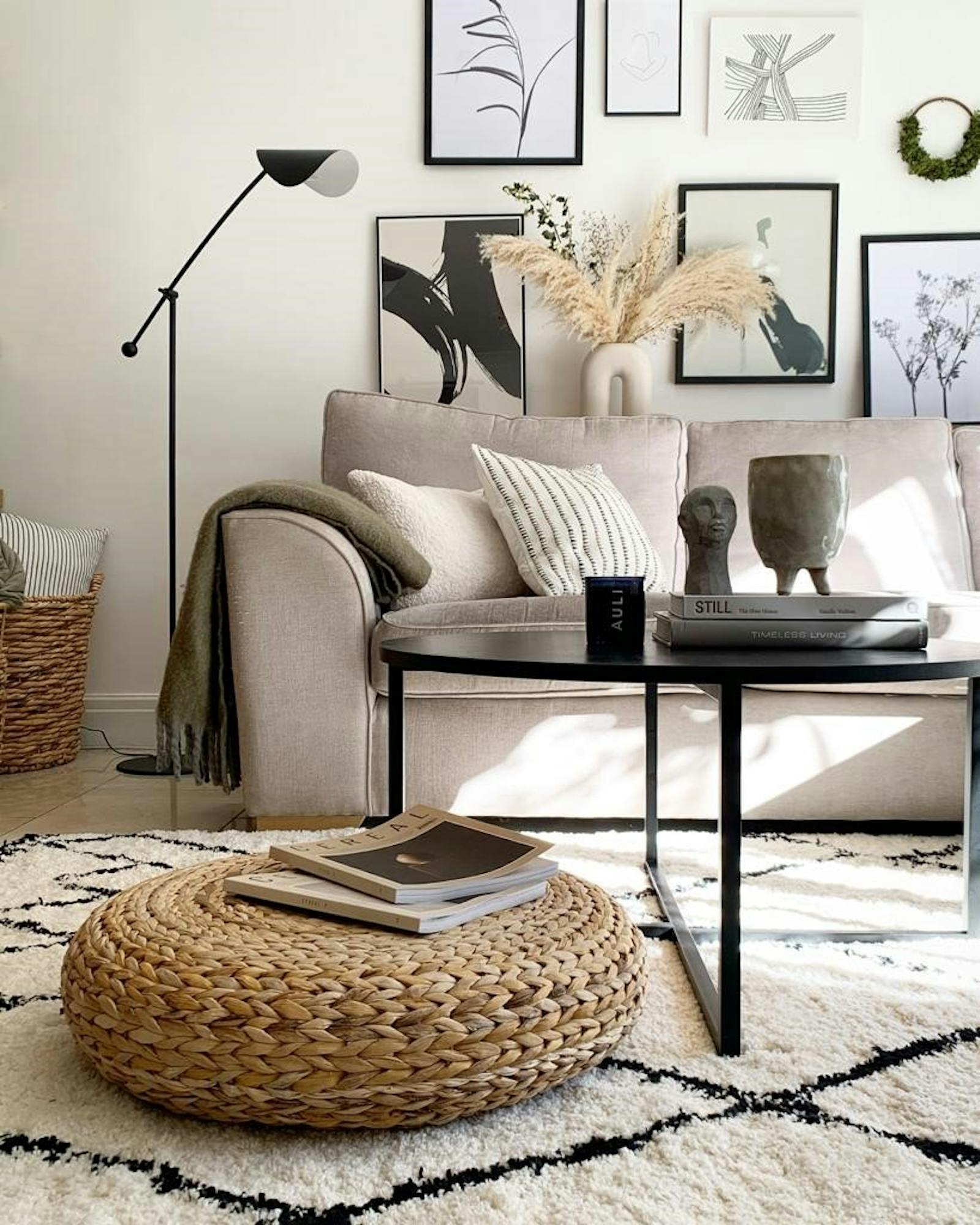 A white wall with various artwork and a sofa with pillows and a throw