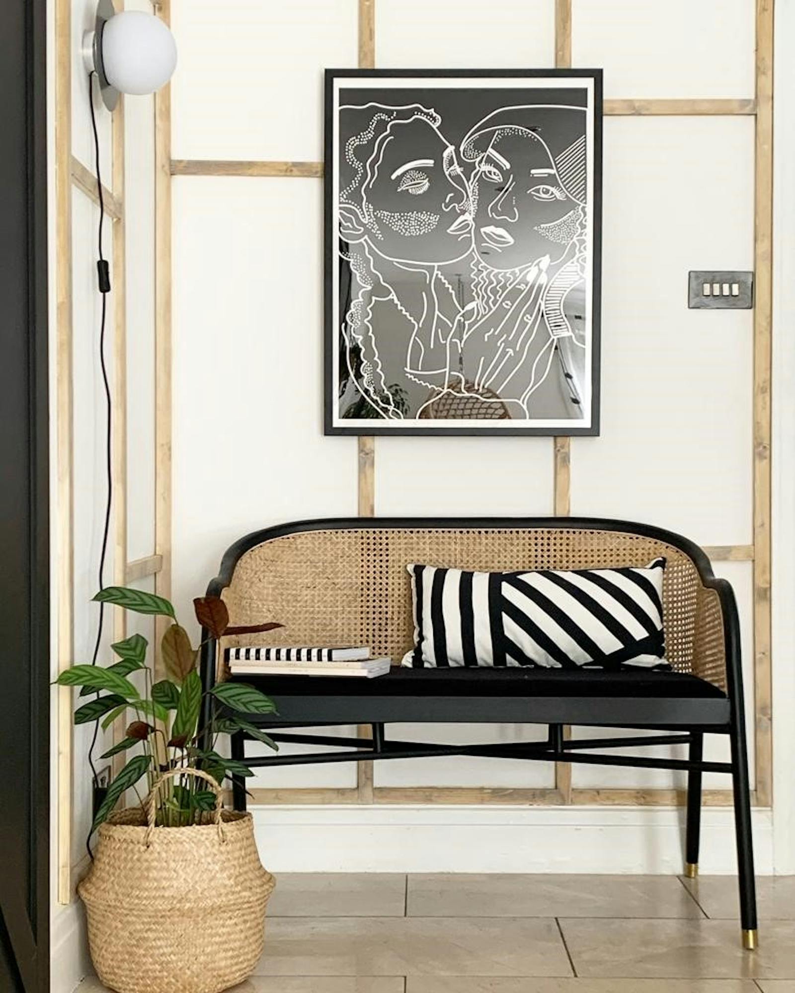 Rattan chair against a white and wooden panelling wall with a black and white patterned cushion on top