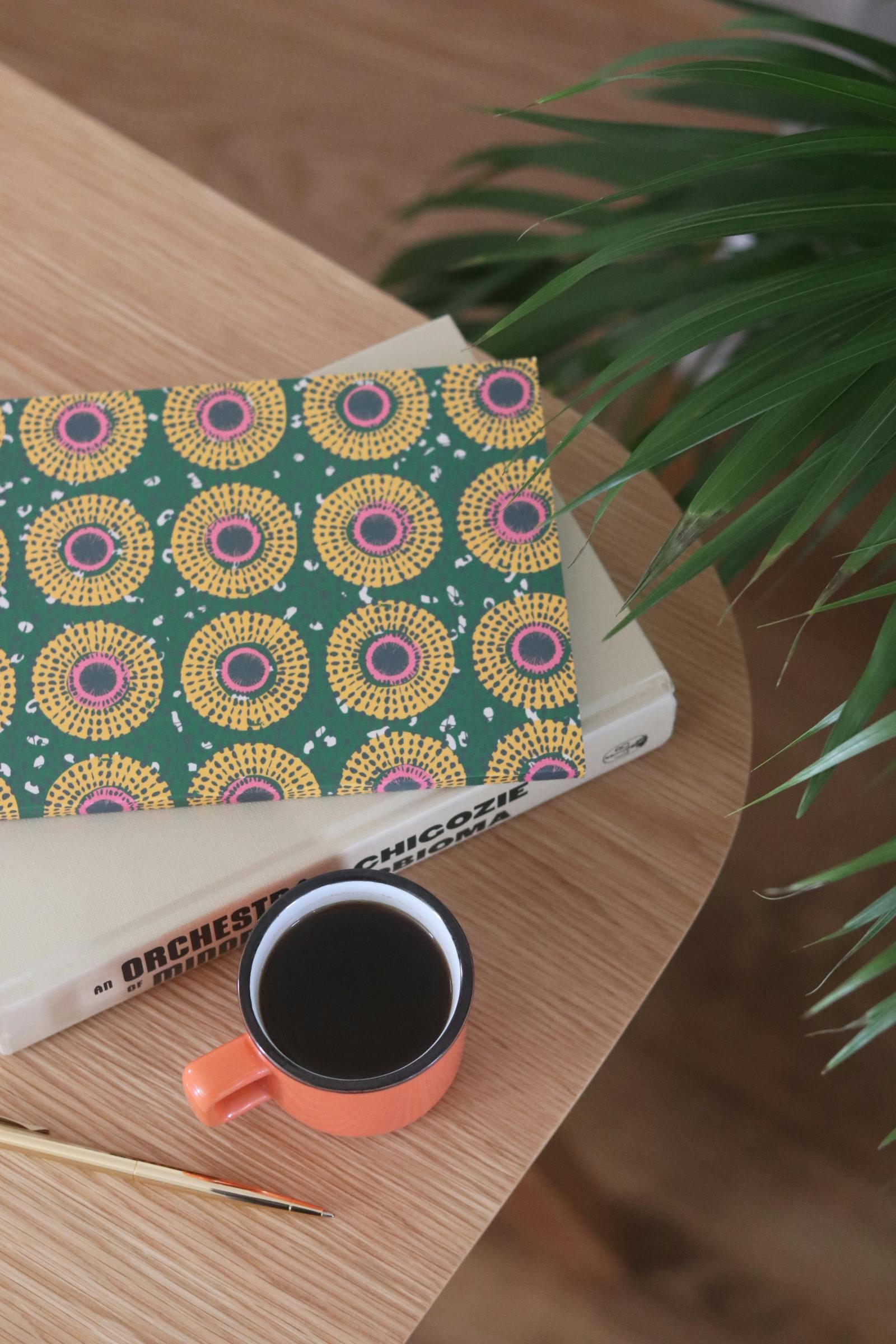 African print notebook next to a cup of coffee