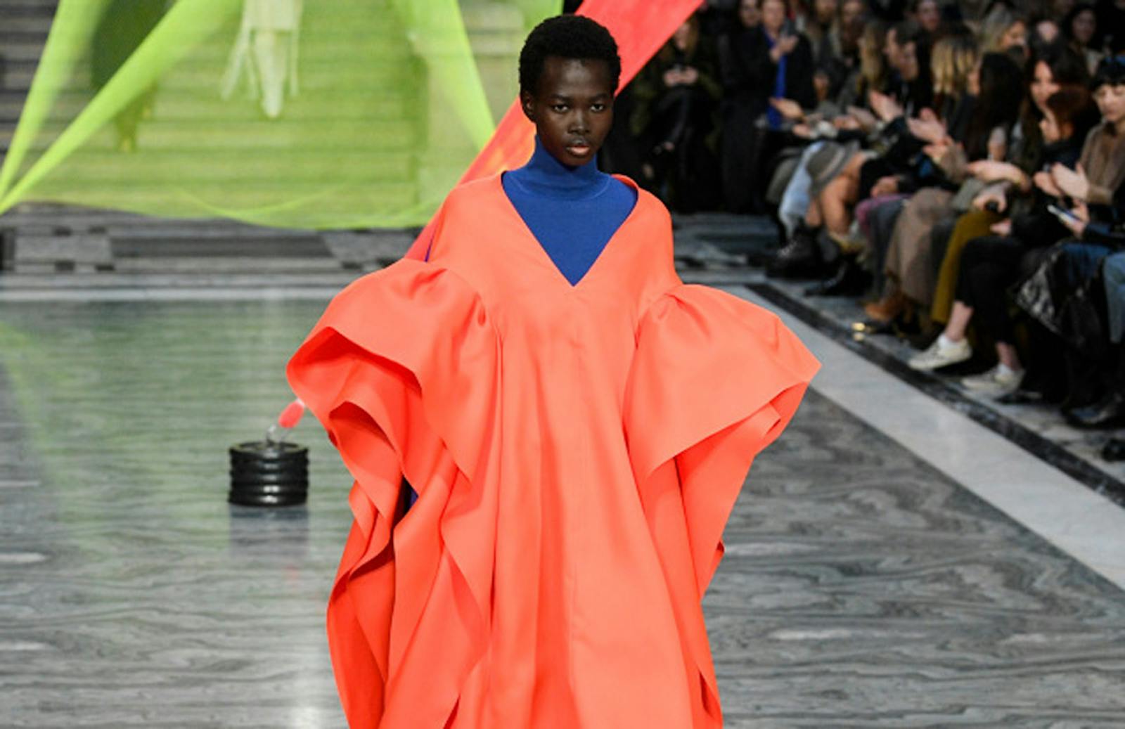 Fashion week shot of woman wearing bright orange dress