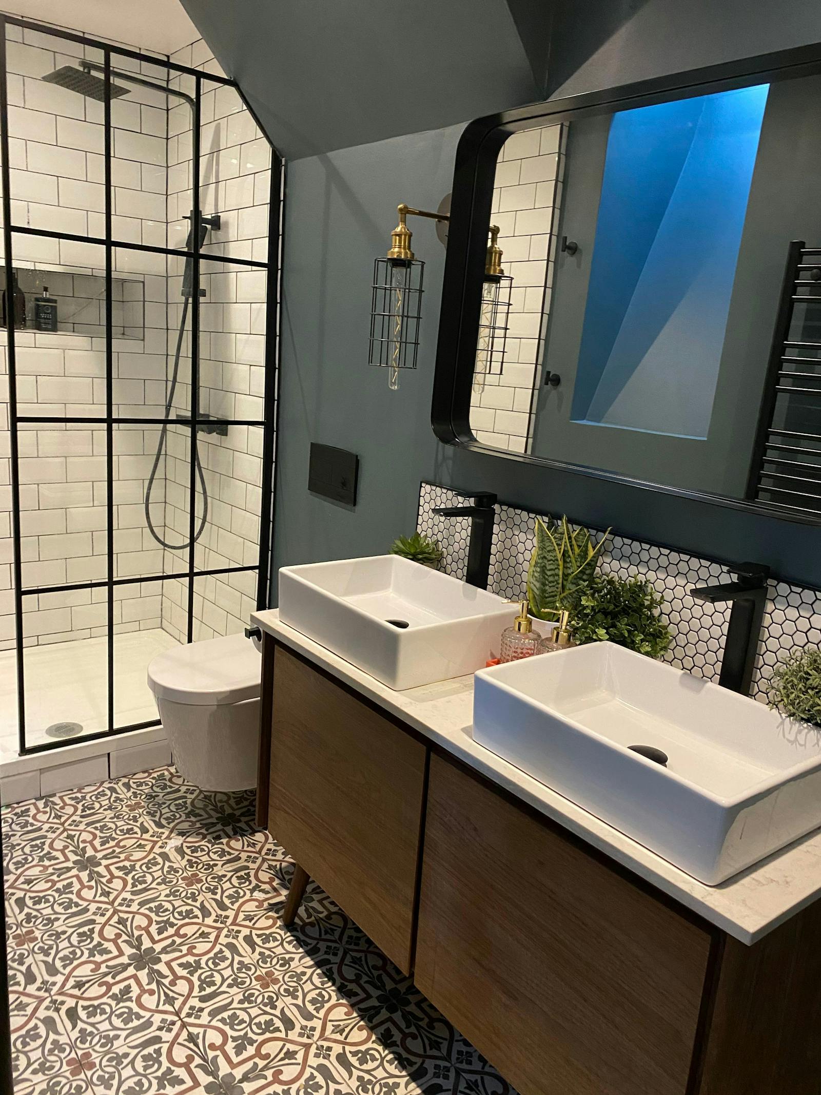 Dark blue bathroom with an assortment of tiles and double sinks