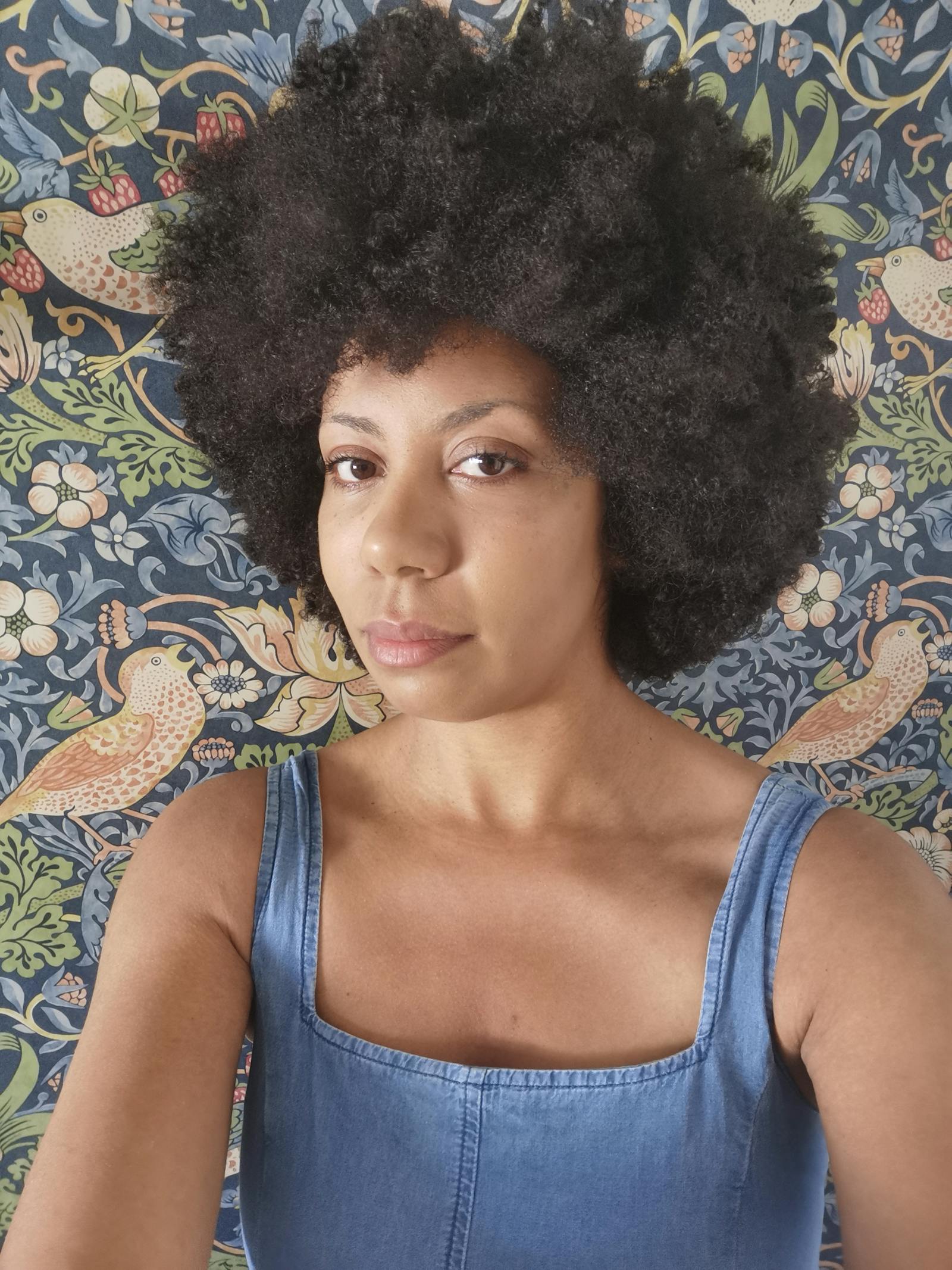 Woman posing in front of a patterned wallpaper
