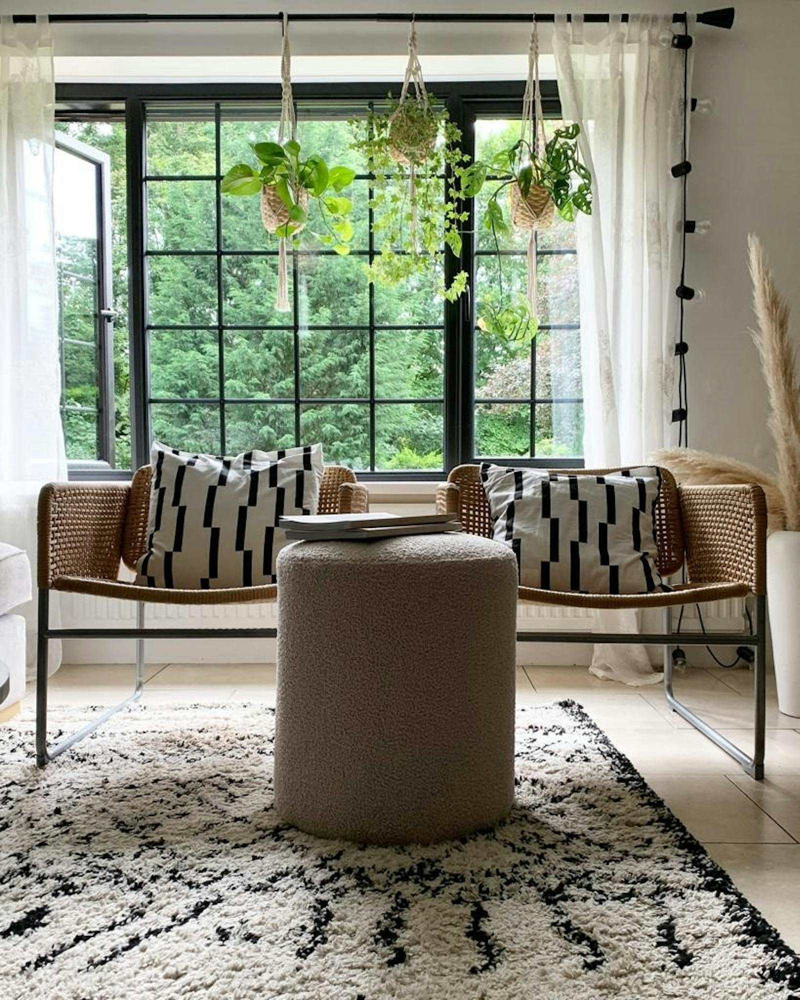 Two chairs in front of big sash windows with black and white patterned cushions