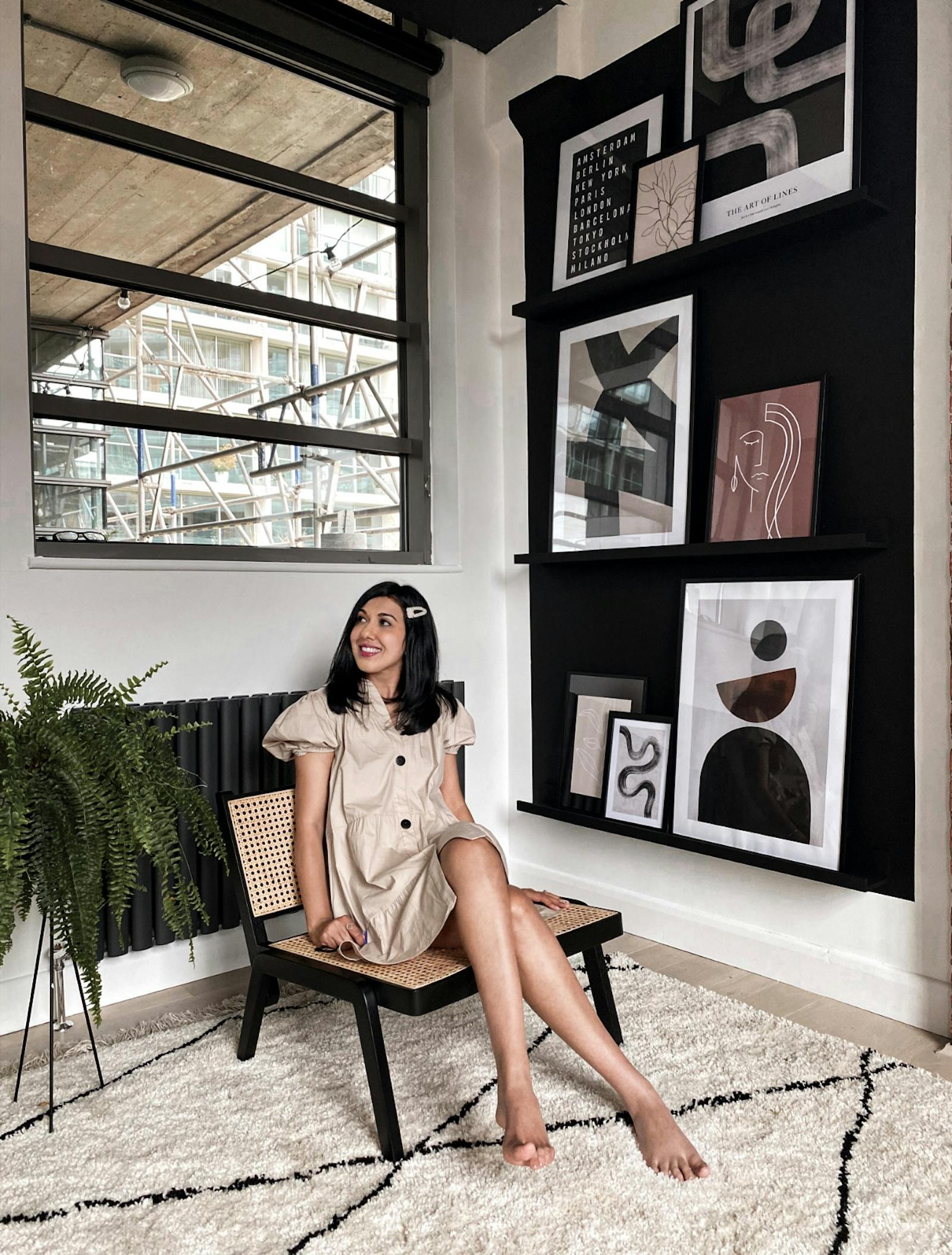 Woman with black hair sitting on a chair in front of a gallery wall