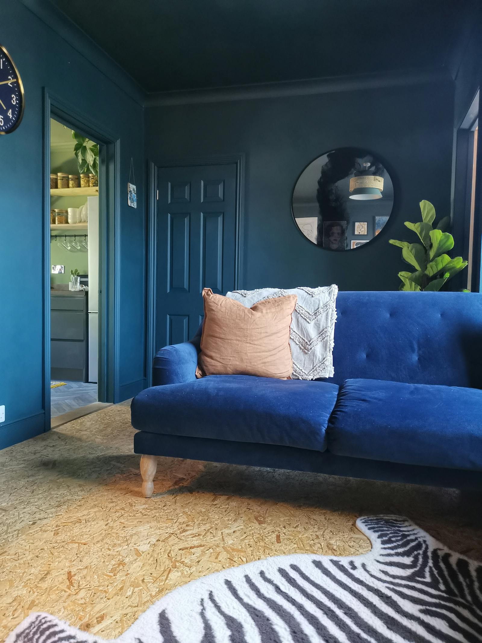 Living room painted in dark blue with a dark blue velvet sofa