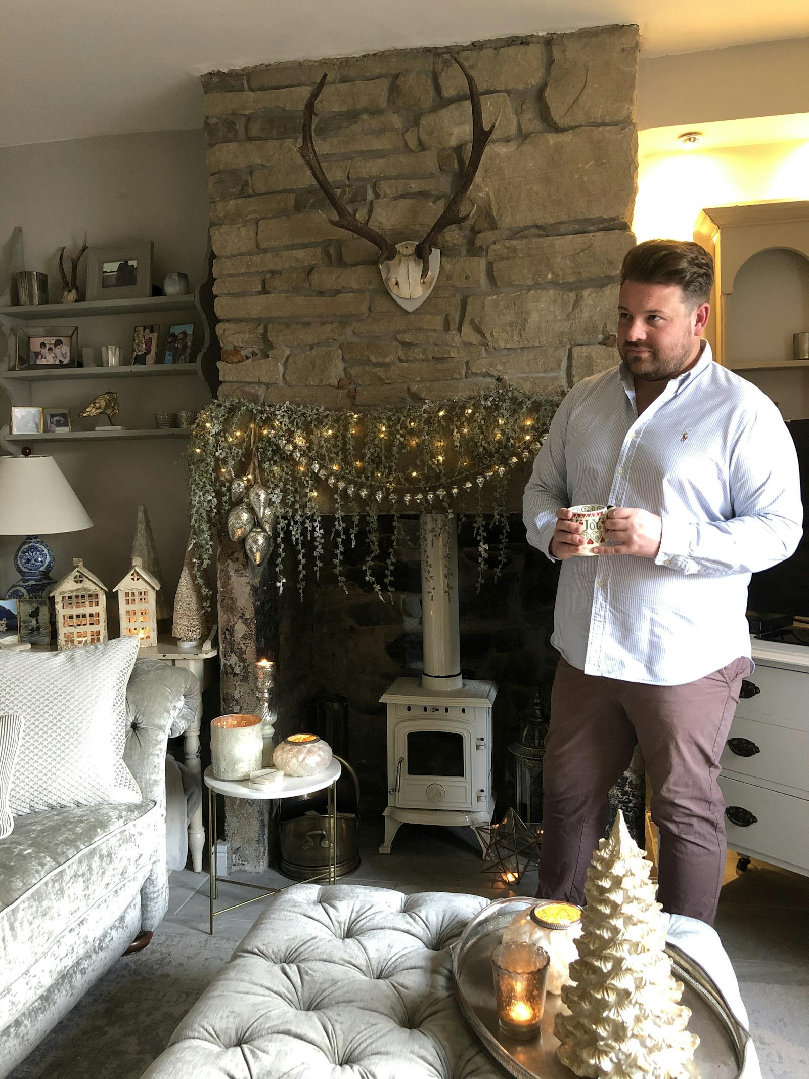 Man standing in front of fireplace decked in Christmas decorations