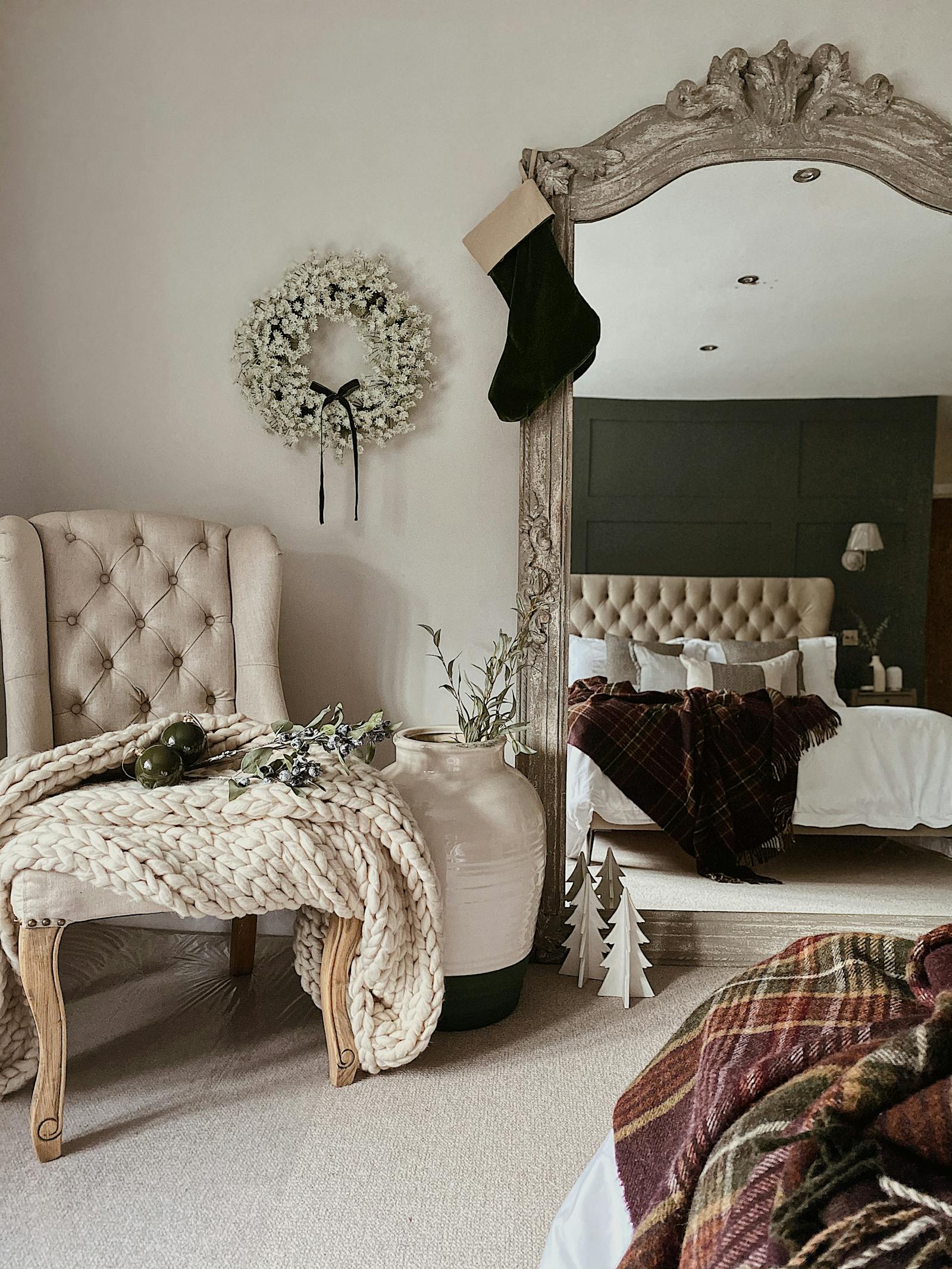 A mirror reflecting into a bedroom, showing a double bed and various amounts of foliage