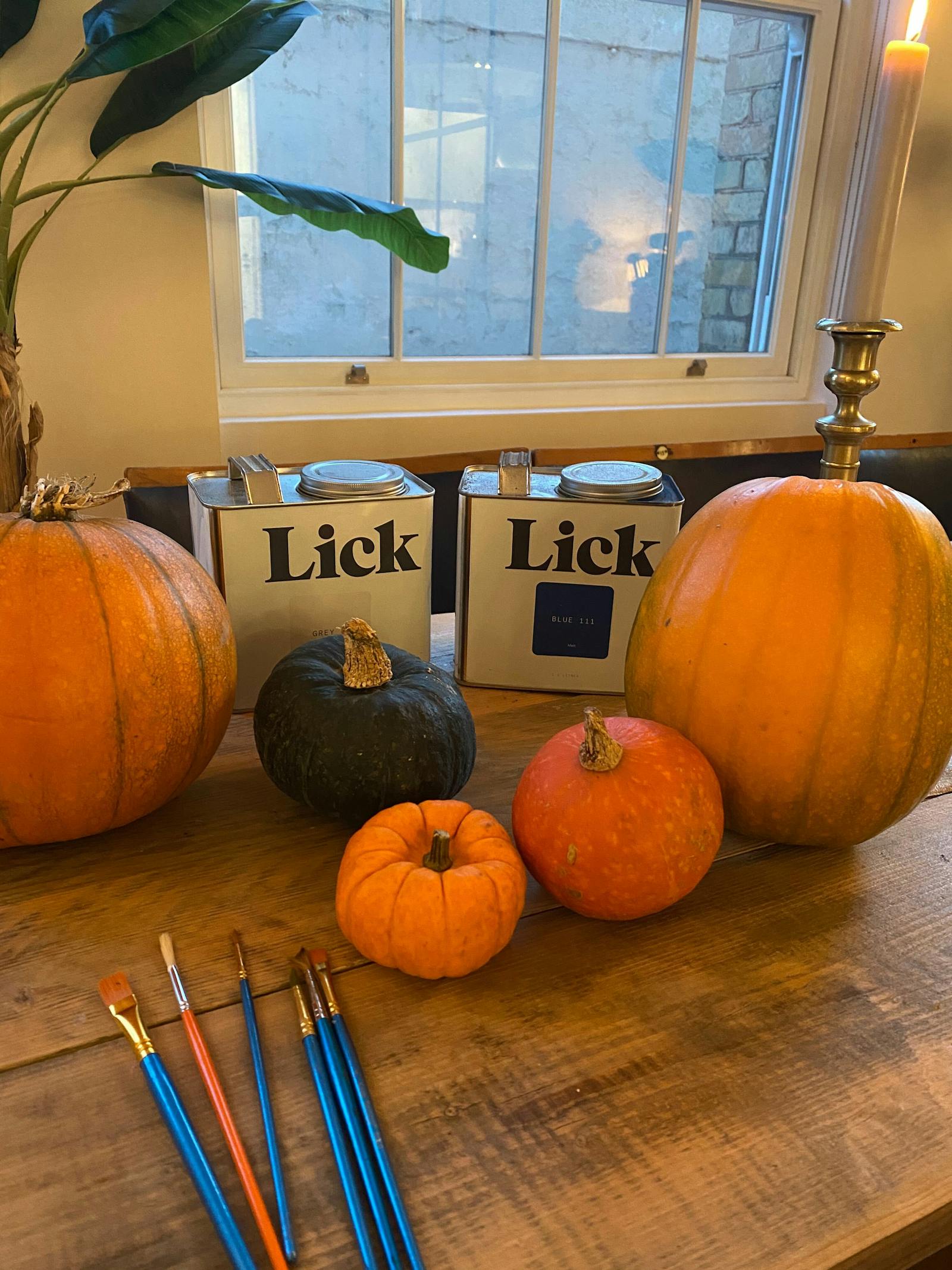 Lick paint tins surrounded by orange and green pumpkins