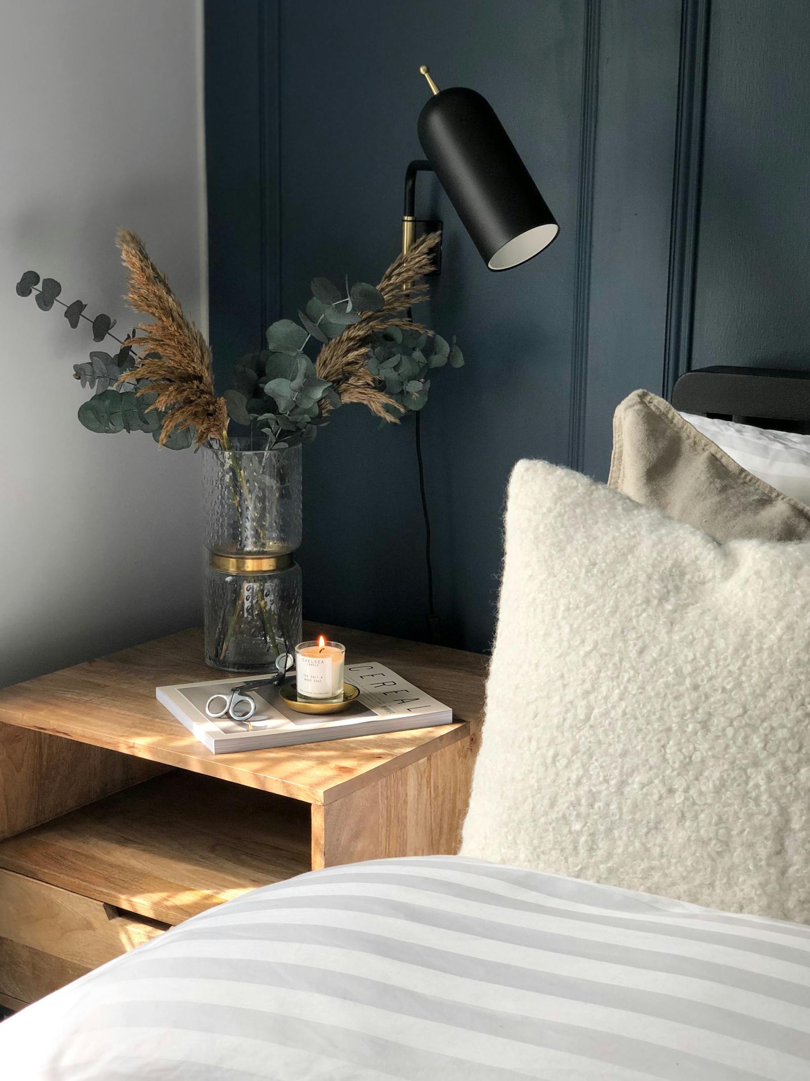 Scandinavian inspired bedroom with dark blue wall panelling, dried flowers and neutral bedding