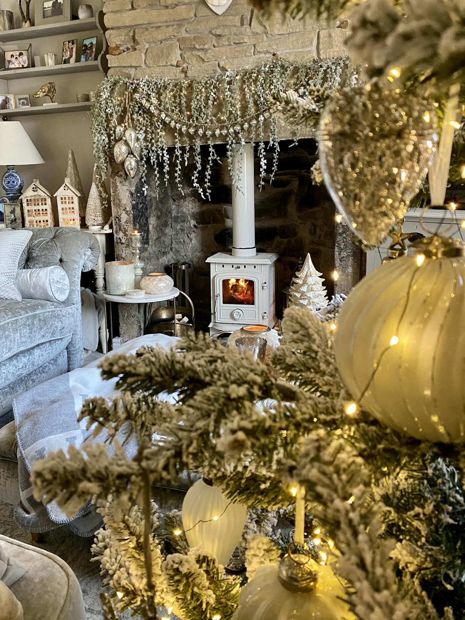 View from behind a Christmas tree looking over to a cozy fireplace