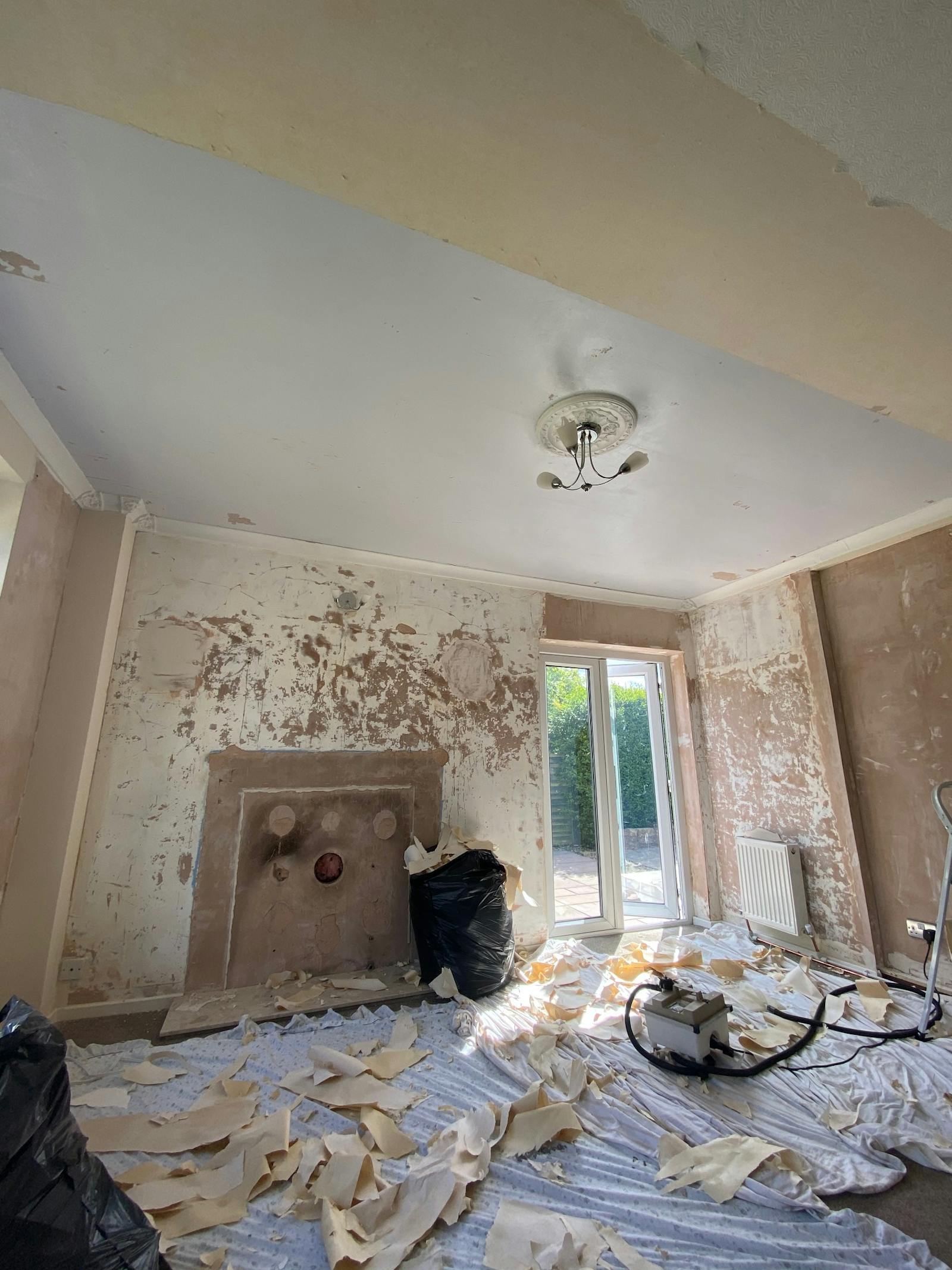 DOAB Before picture of room with peeling plaster and decorating equipment