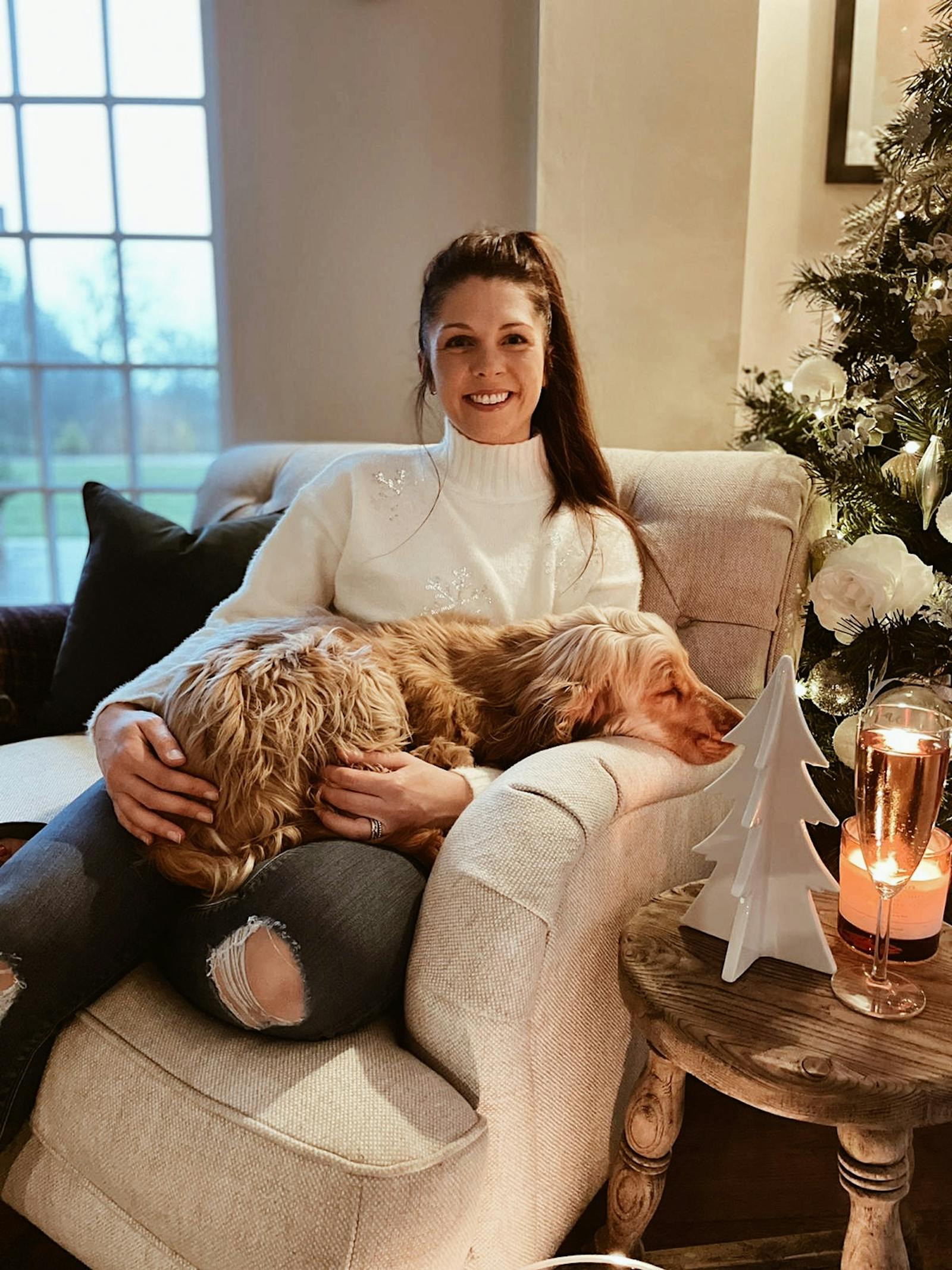 Brunette woman sitting on chair holding a sleeping dog