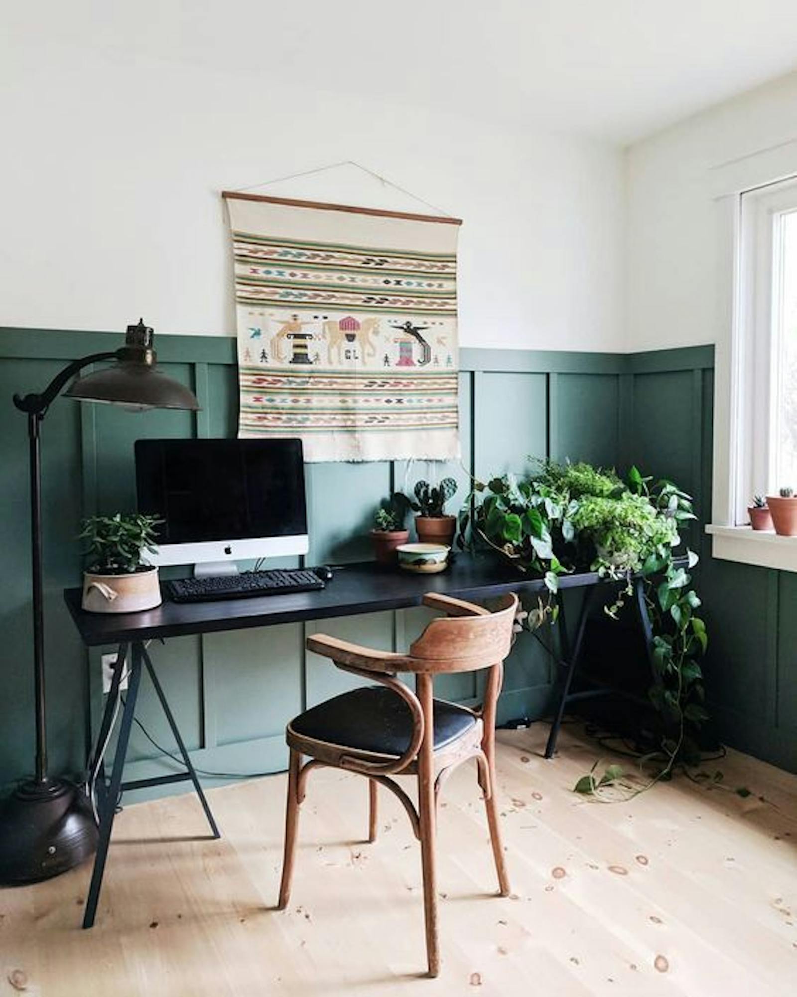 Home office area with a two-tone wall painted in white and green, wooden chair and green plants